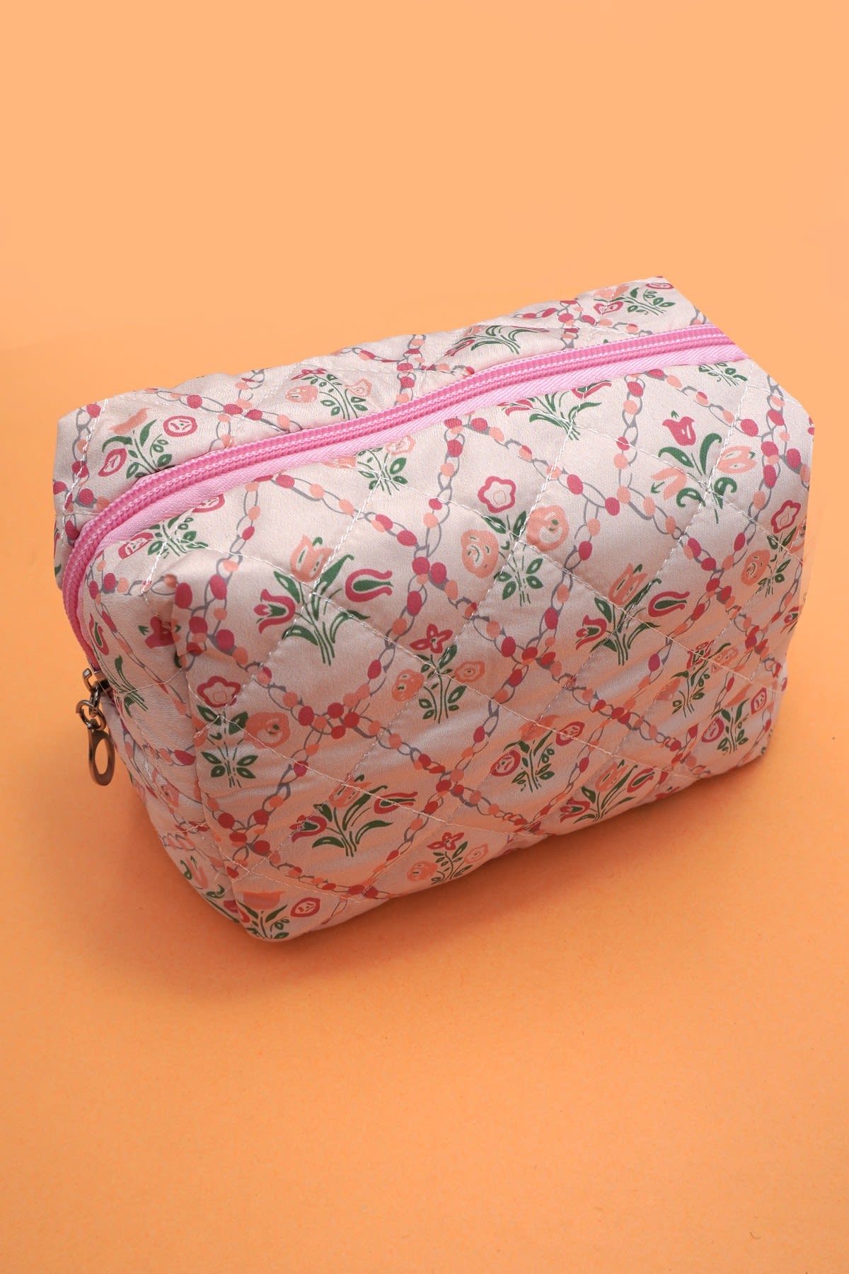 Quilted Pink Floral Cosmetic Bag - A delightful blend of functionality and charm designed to elevate your makeup storage. It offers ample space to organize your cosmetics, brushes, and beauty essentials. Whether you're traveling or simply organizing your vanity, this pouch is perfect for keeping your makeup items secure and easily accessible.   Item Description: Length: 7" height: 4" depth: 3" Zip closure