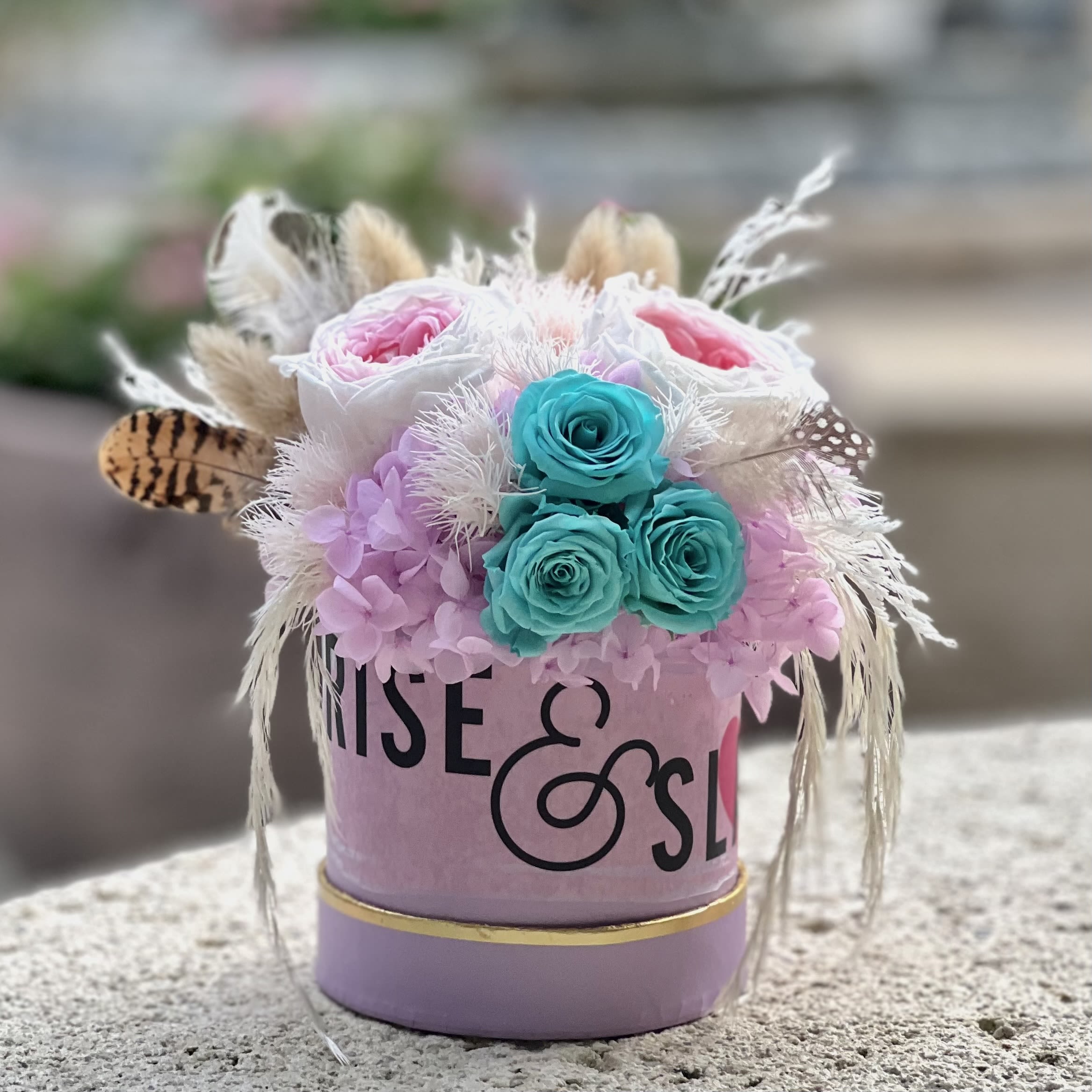 Whimsical Bloom Eternal Bouquet - The Whimsical Bloom Eternal Bouquet is a charming mix of pink hydrangeas, blue mini roses, garden roses, and cute feathers, accented with delicate dried elements. Presented in a petite lavender flower box, this small yet vibrant arrangement brings a pop of color and playful elegance to any space. A luxurious, eco-friendly gift that lasts, it’s the perfect low-maintenance, sustainable alternative to fresh flowers, offering timeless beauty with a joyful, colorful twist.