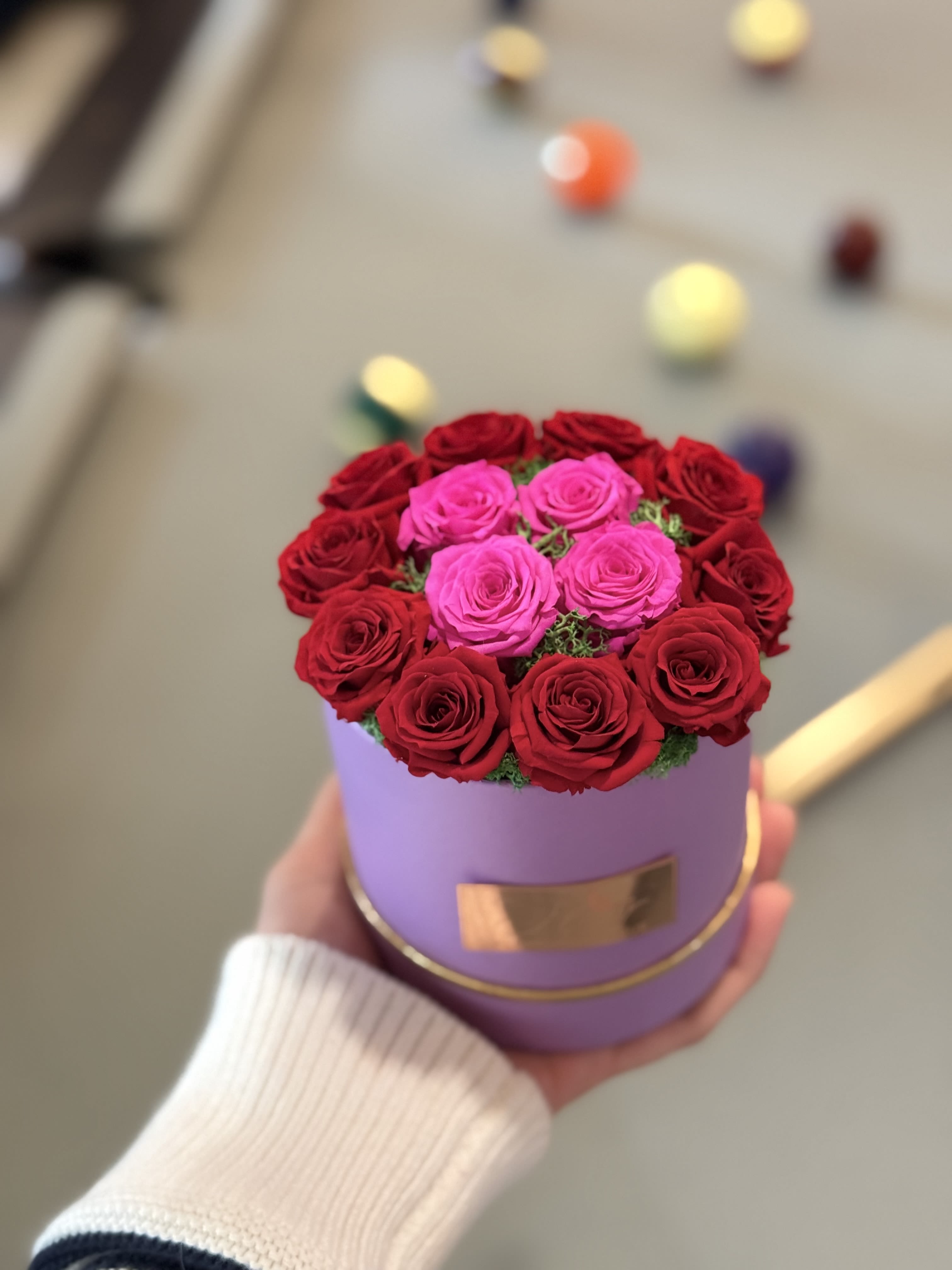 Mini Color Cue  - A stunning mini arrangement featuring preserved lavender, hot pink, and red roses in a smooth ombré effect, nestled in green moss. Designed for long-lasting beauty, this vibrant piece adds a touch of elegance with a playful twist, set against the colorful backdrop of billiard balls. Perfect for any space!