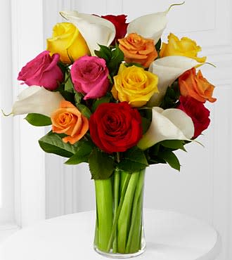 Mixed roses and Calla lilies  - The Mixed Roses and Calla Lily Bouquet a fresh burst of blooming cheer and charm to your special recipient to make this day unlike any other moment in their life! A beautiful assortment of roses in the shades of hot pink, orange, yellow and red are perfectly offset by elegant open cut white calla lilies and accented with an assortment of lush greens to create a fantastic flower arrangement. Presented with a classic clear glass vase, this mixed flower bouquet will convey your warmest wishes to bring color and life to their birthday, anniversary, or graduation celebration.  To guarantee the freshest bouquet possible, we may replace some stems in your arrangement for color or flower variety. While we always do the best to match the picture shown, sometimes different vases may be used. Any substitution made will be similar to the original design and be of equal or greater value.