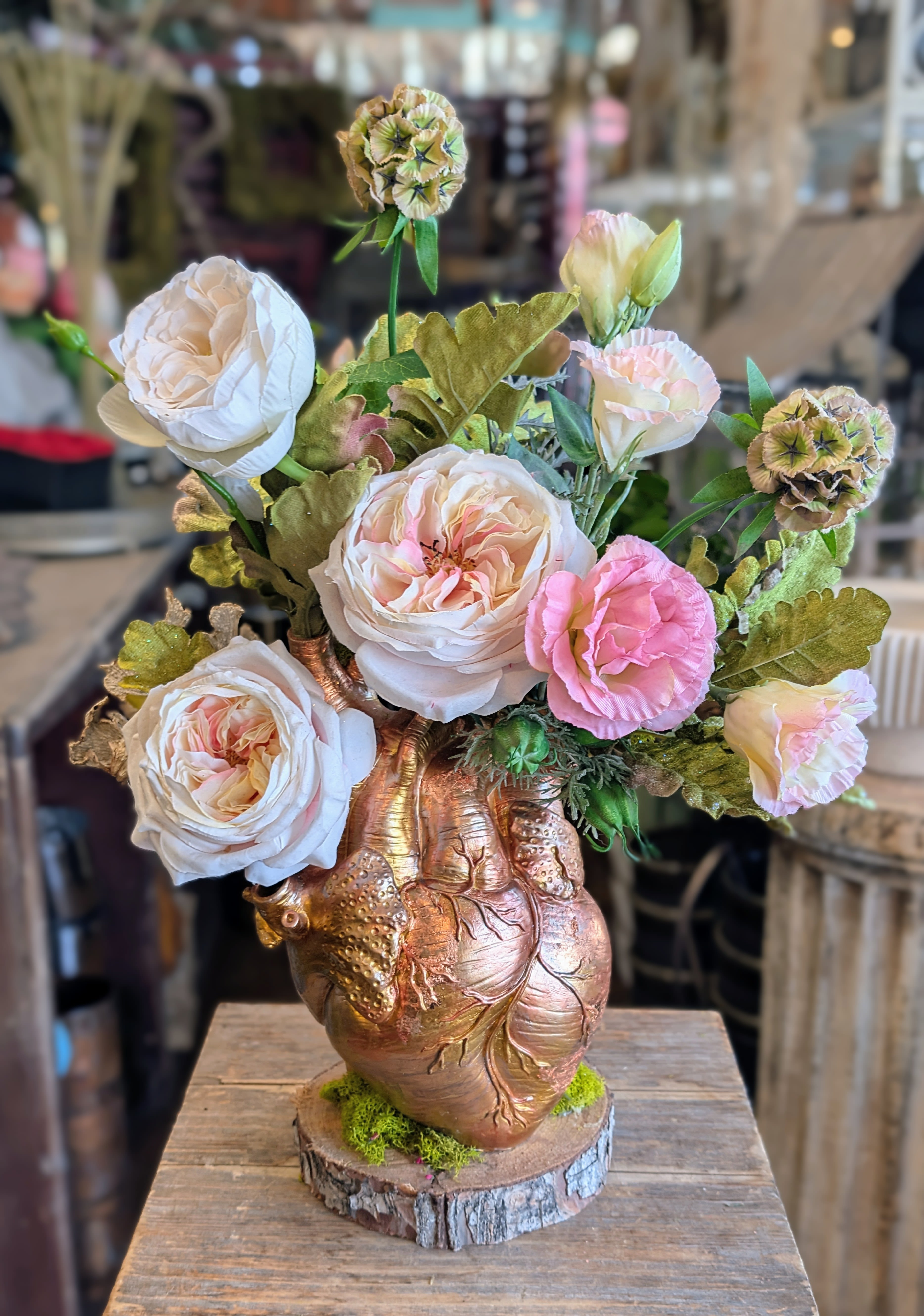 Wildheart- A Permanent Botanical - Wildheart is a poetic union of anatomy and florals — a permanent botanical arrangement from Windmill Floral Expressions that celebrates love in its rawest, most beautiful form. Designed in a sculptural heart vessel featuring hand-applied copper leaf accents, this striking piece overflows with lush blush and ivory garden roses, soft pink lisianthus blooms, sculptural greenery, and textured botanical accents, creating a romantic composition that feels both wild and reverent.  Handcrafted in Las Vegas by Windmill Floral Expressions, Wildheart is created using premium faux and preserved florals for lasting beauty without maintenance. Each stem is thoughtfully placed to evoke movement and emotion — blending vintage romance with modern mysticism. The heart-shaped vessel offers a bold, symbolic foundation, making this piece a true floral sculpture and conversation starter.  Perfect as a Valentine’s Day gift, anniversary keepsake, or meaningful home décor accent, Wildheart is ideal for clients seeking luxury permanent florals in Las Vegas and Henderson. This everlasting arrangement brings boho elegance and soulful charm to shelves, entry tables, offices, and sacred spaces, offering a timeless alternative to fresh flowers.  Whether you’re searching for a unique Valentine’s gift, artistic floral décor, or custom permanent botanicals in Las Vegas, Wildheart delivers expressive design with enduring impact. Designed to be treasured year-round — no watering required, just admiration.