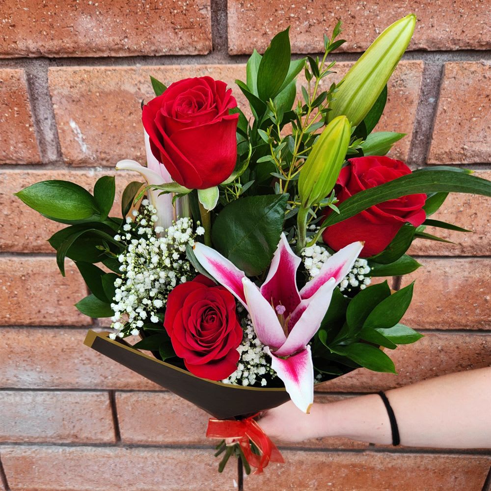 Hand-tied Bouquet of Red Roses and Stargazer Lilies - Luxurious long-stem red Ecuadorian Mountain roses and fragrant pink stargazer lilies nestled in Israeli ruscus sprays, fresh garden greens and seasonal filler. A message of love unfurls with every petal. This bouquet is hand arranged by our designers and available for pickup only.  Standard - 3 Red Roses, 1 Stargazer Lily (2-3 Blooms), Fresh Garden Greens and Filler - Wrap  Deluxe - 6 Red Roses, 2 Stargazer Lilies (4-6 Blooms), Fresh Garden Greens and Filler - Wrap  Premium - 12 Red Roses, 3 Stargazer Lilies (6-9 Blooms), Fresh Garden Greens and Filler - Wrap  Please Note: Upon delivery most lilies will be in bud form to ensure freshness and extended flower's life span. As with any lily, the stamens should be plucked off as soon as they present themselves from within the flower. This will enhance the life of the flower and prevent staining from the pollen.  This bouquet does not include a vase, and the rose stems require a sharp fresh cut before placing your bouquet in water. We recommend placing your bouquet in fresh water within an hour of picking it up from our store. This process will ensure extended flower's life span.