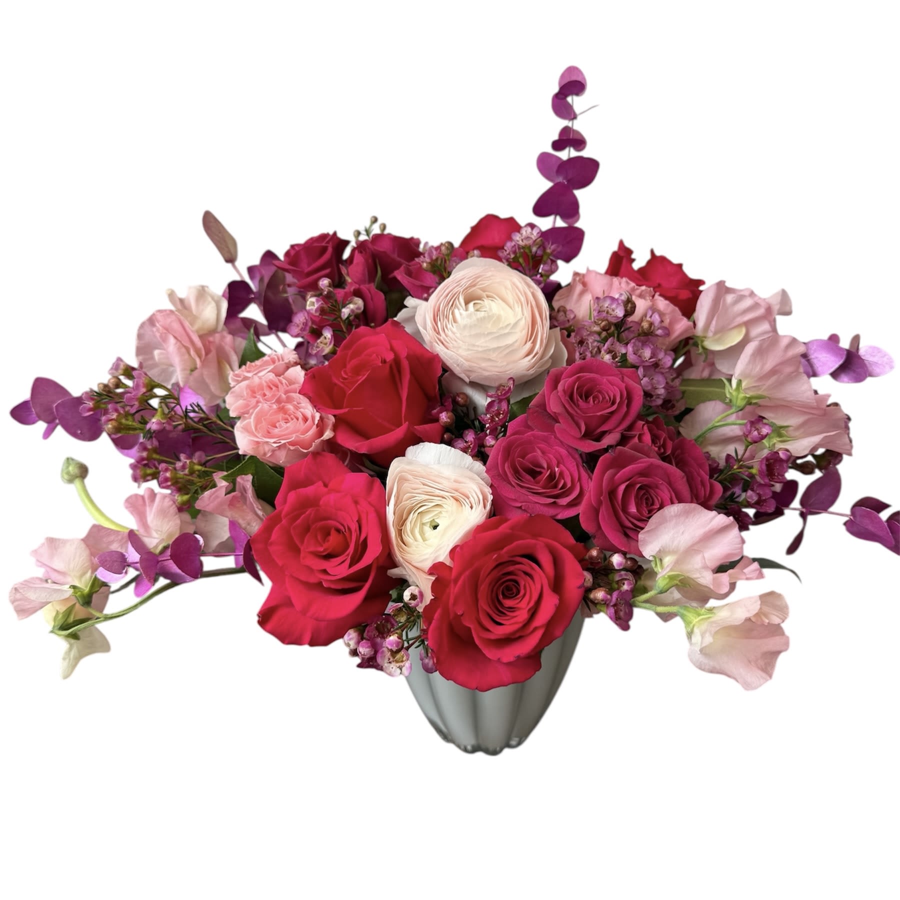 Blushing Hearts  - Hot pink roses, pink ranunculus, pink spray roses, hot pink spray roses, sweet pea, wax flower, eucalyptus designed in a white glass vase. As shown in photo.