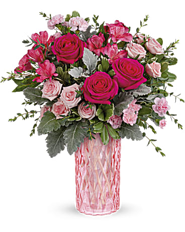 Teleflora's Love's Reflection Bouquet - Inspired by elegant vintage perfume bottles of years past, this glorious pink keepsake vase features a diamond-cut pattern that sparkles in the light. It's the perfect presentation for this flirtatious pink rose bouquet! Hot pink roses, miniature pink carnations, dark pink alstroemeria and light pink spray roses are arranged with parvifolia eucalyptus, dusty miller and variegated pittosporum. Delivered in Teleflora's Love's Reflection vase.