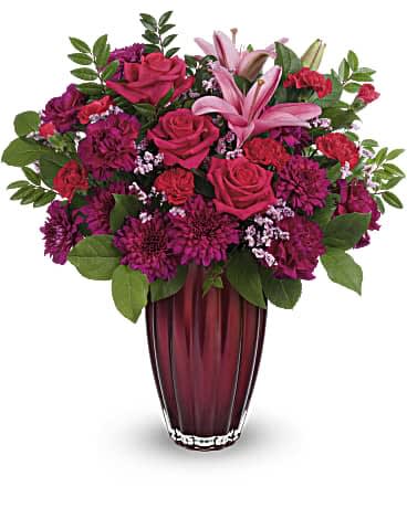 Teleflora's Modern Devotion Bouquet - Your devotion knows no bounds. Celebrate your love with this stunning rose and lily bouquet, artfully arranged in a magnificent European glass vase with pearlescent finish. This arrangement includes hot pink roses, pink asiatic lilies, fuchsia carnations, miniature red carnations, pink cushion spray chrysanthemums, pink limonium, lemon leaf and huckleberry. Delivered in Teleflora's Modern Devotion vase. Orientation: All-Around