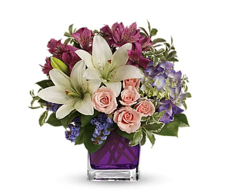 Garden Romance - Hello, gorgeous! This lovely bouquet includes purple hydrangea, light pink spray roses and white asiatic lilies arranged in our vibrant violet glass cube. Purple hydrangea, light pink spray roses, white asiatic lilies, dark pink alstroemeria and lavender sinuata statice are accented with assorted greens. Delivered in Teleflora's glass violet cube.   Orientation : One-Sided  All prices in USD ($)  Standard  TEV20-1A  Deluxe  TEV20-1B  Premium  TEV20-1C