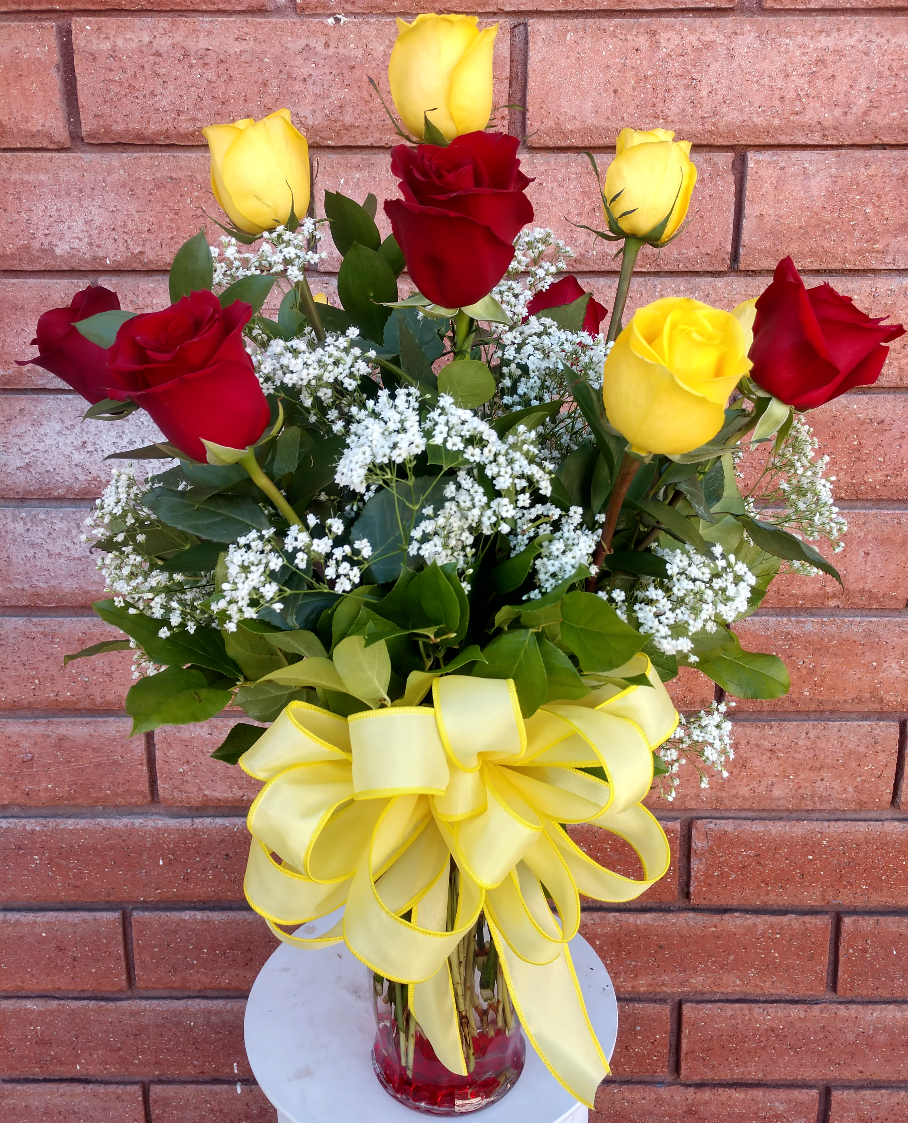 Long Stem Red And Yellow Roses Vase - A perfect rose arrangement to display feelings of love with vibrancy and enthusiasm. The yellow helps to represent the sun, the giver of all life and a symbol of happiness, and the red explains the deep passion of your feelings. Hand-picked premium long stem roses are professionally arranged with Gypsophila (Baby's Breath) and fresh garden greens, in a clear glass vase with a big bow. Standard size is approximately 20in (W) x 28in (H). Deluxe and Premium versions are larger and feature more roses, hand arranged in larger glass vases.  Standard – One Dozen (12) Long Stem Red and Yellow Roses, Fresh Garden Greens &amp; Fillers - Glass Vase  Deluxe – Two Dozen (24) Long Stem Red and Yellow Roses, Fresh Garden Greens &amp; Fillers - Glass Vase  Premium – Three Dozen (36) Long Stem Red and Yellow Roses, Fresh Garden Greens &amp; Fillers - Glass Vase  Care Tips: Place your bouquet in a cool location. Don't put the arrangement in direct sunlight, near heating or cooling vents, in drafty places, directly under ceiling fans, or on top of televisions or radiators. Check water level daily, keep the vase full with clean water. Change water every 2-3 days and apply a sharp fresh cut to the stems. This process will ensure extended flower's life span.
