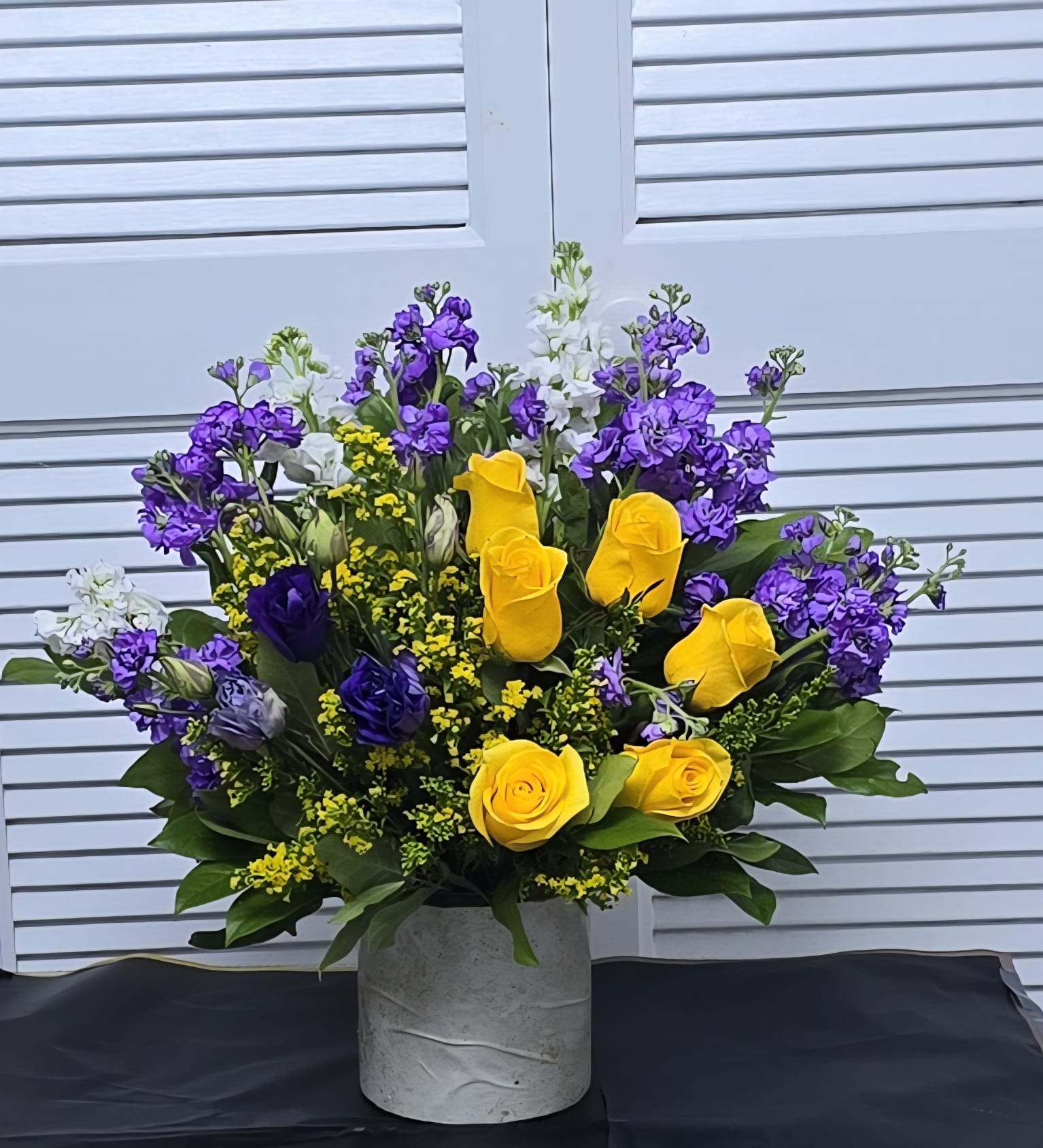 Royal Sunshine Arrangement - A vibrant and eye-catching arrangement featuring bright yellow roses paired with rich purple blooms and fresh seasonal greenery. Designed in a modern ceramic container, this bouquet brings a bold pop of color and joyful elegance to any occasion. Perfect for celebrating milestones or sending a cheerful surprise.