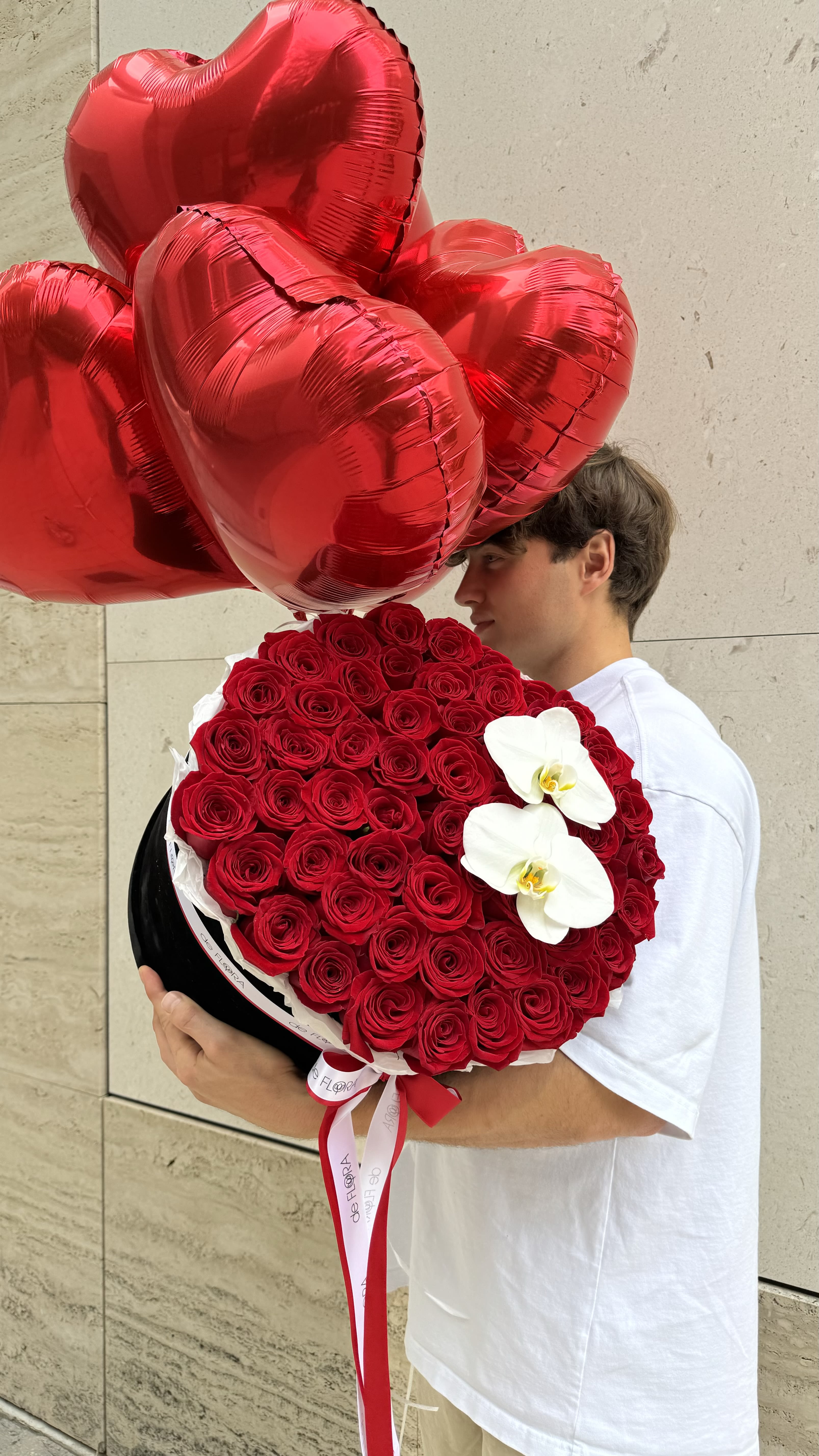 Grand Gesture of Love - Luxury Rose and Orchid Arrangement (Balloons are not included) Make a breathtaking statement with this stunning bouquet featuring a lush arrangement of premium red roses, symbolizing deep love and passion. Delicately accented with elegant white orchids, this floral masterpiece exudes sophistication and charm. Presented in a stylish hatbox and adorned with romantic ribbons, it’s the perfect gift for anniversaries, birthdays, or just to express your love in an unforgettable way.  Want to impress someone special? Order now and let your love bloom beautifully!  Available for delivery. Contact us today!