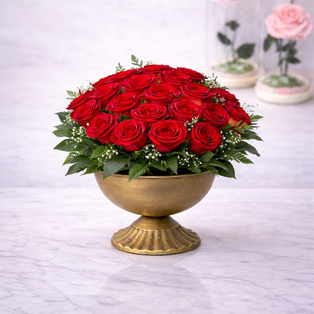 Golden Red Rose Centerpiece™ - A timeless and elegant arrangement featuring lush premium red roses, accented with delicate baby’s breath and fresh greenery, all designed in a classic gold pedestal bowl. This romantic centerpiece blends luxury and sophistication, making it a stunning statement for any special occasion. BloomNation’s Premium option includes a white orchid accent, adding an elevated, refined touch for an even more luxurious presentation.  Better for: Valentine’s Day, anniversaries, romantic gestures, luxury gifts, engagement celebrations, I love you, elegant home décor, special moments. 