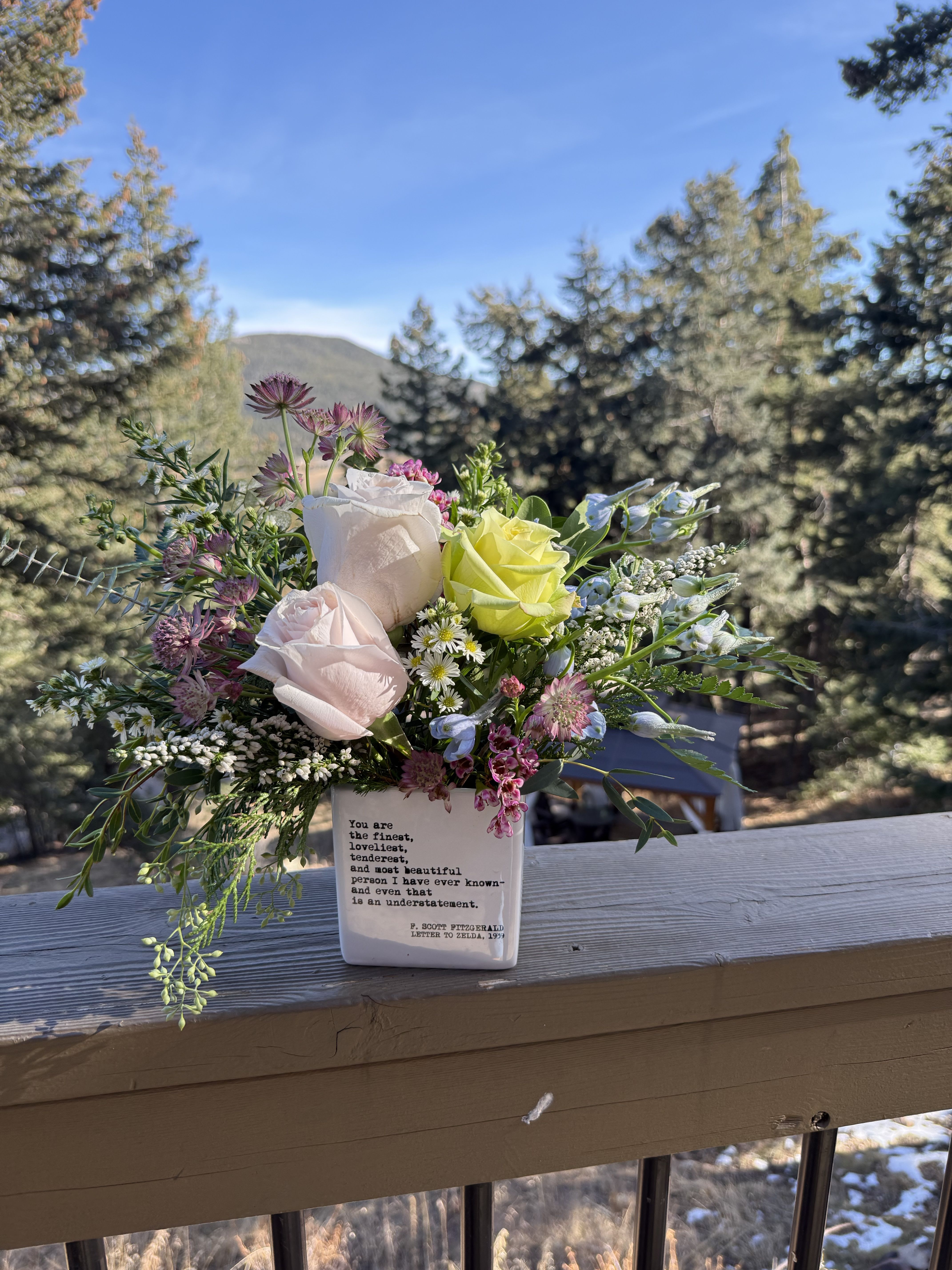 The Zelda - The first original flapper lived a rich, dramatic, and artistic life being a muse and an accomplished artist herself.  “ You are the finest, loveliest, tenderest, and most beautiful person I have ever known- and even that is an understatement.” F. Scott Fitzgerald to Zelda, 1939  The Zelda was inspired by her quick wit, artistic endeavors, and the great love affair between Zelda and F. Scott Fitzgerald.  The cube is emblazoned with words of affection and highlights and interesting selection pastel flowers and textural greenery to create a sophisticated, low and lush arrangement suitable for many locations and occasions. Most people are unaware of Zelda’s accomplished ballet career and this arrangement uses colors and flowers inspired by the pastel hues often associated with the classical form of ballet. 