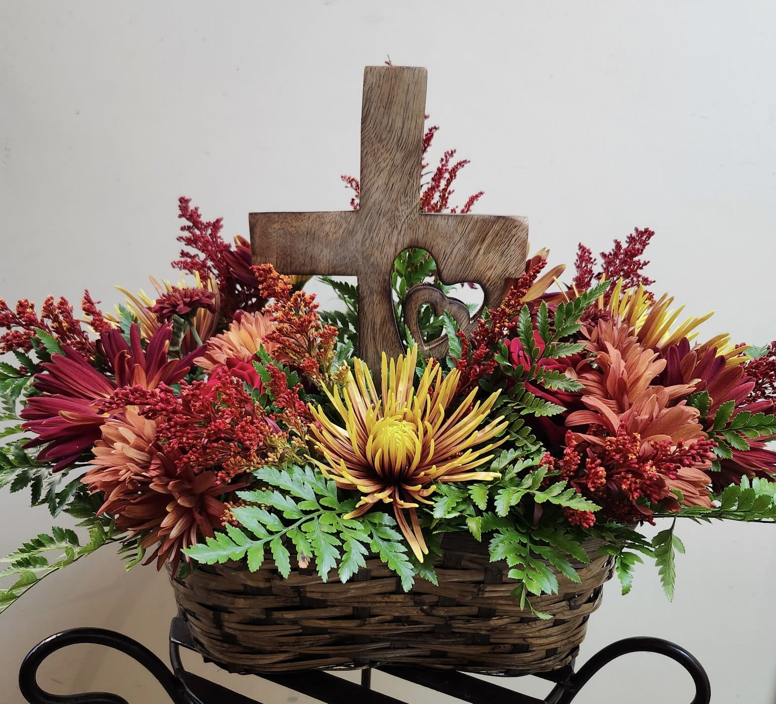 Our Hearts Go Out To You - A rugged keepsake wooden "cross" heart is displayed within a collection of seasonal flowers chosen by the Designer according to availability/seasonality.  