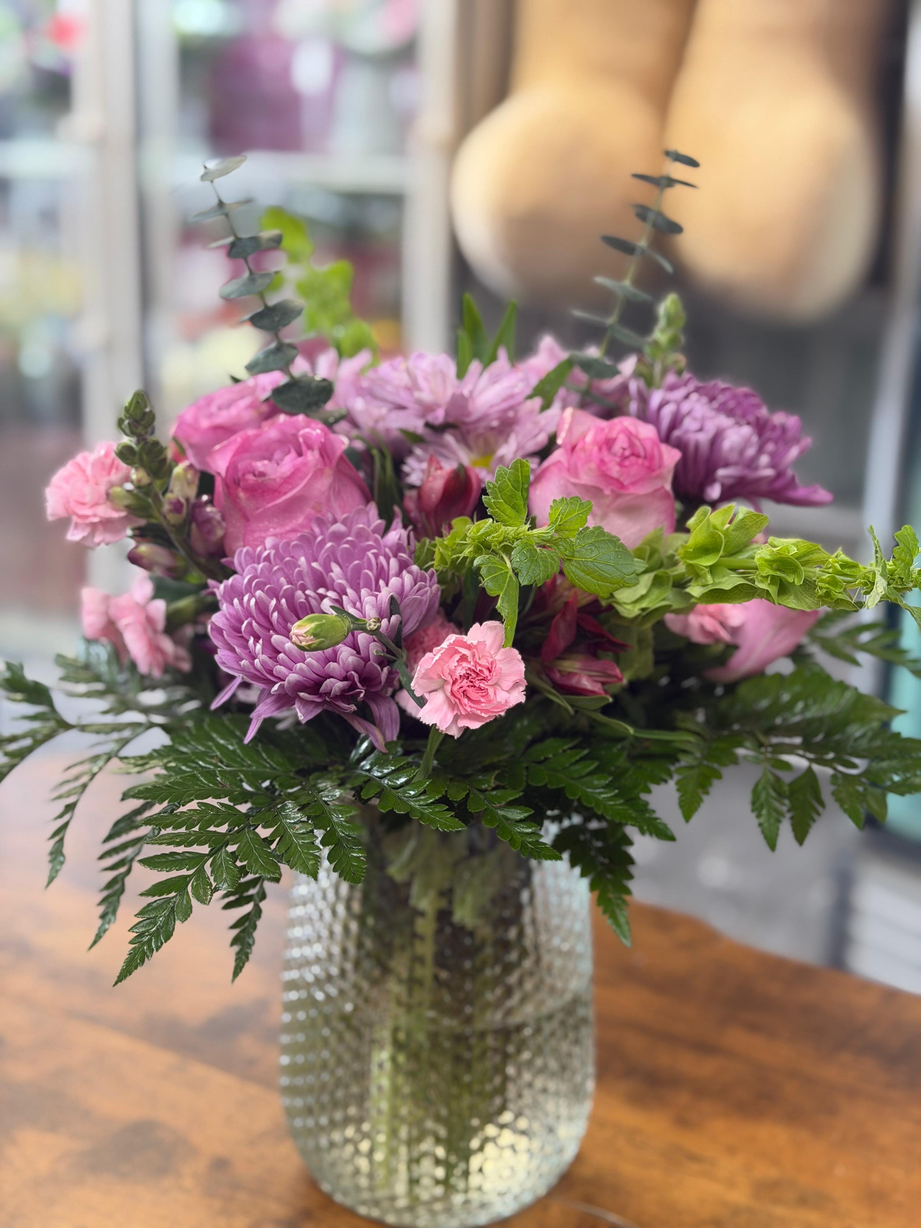 jarro alegria - consiste en una base de agua clear con follaje verde y flores  morados rosado