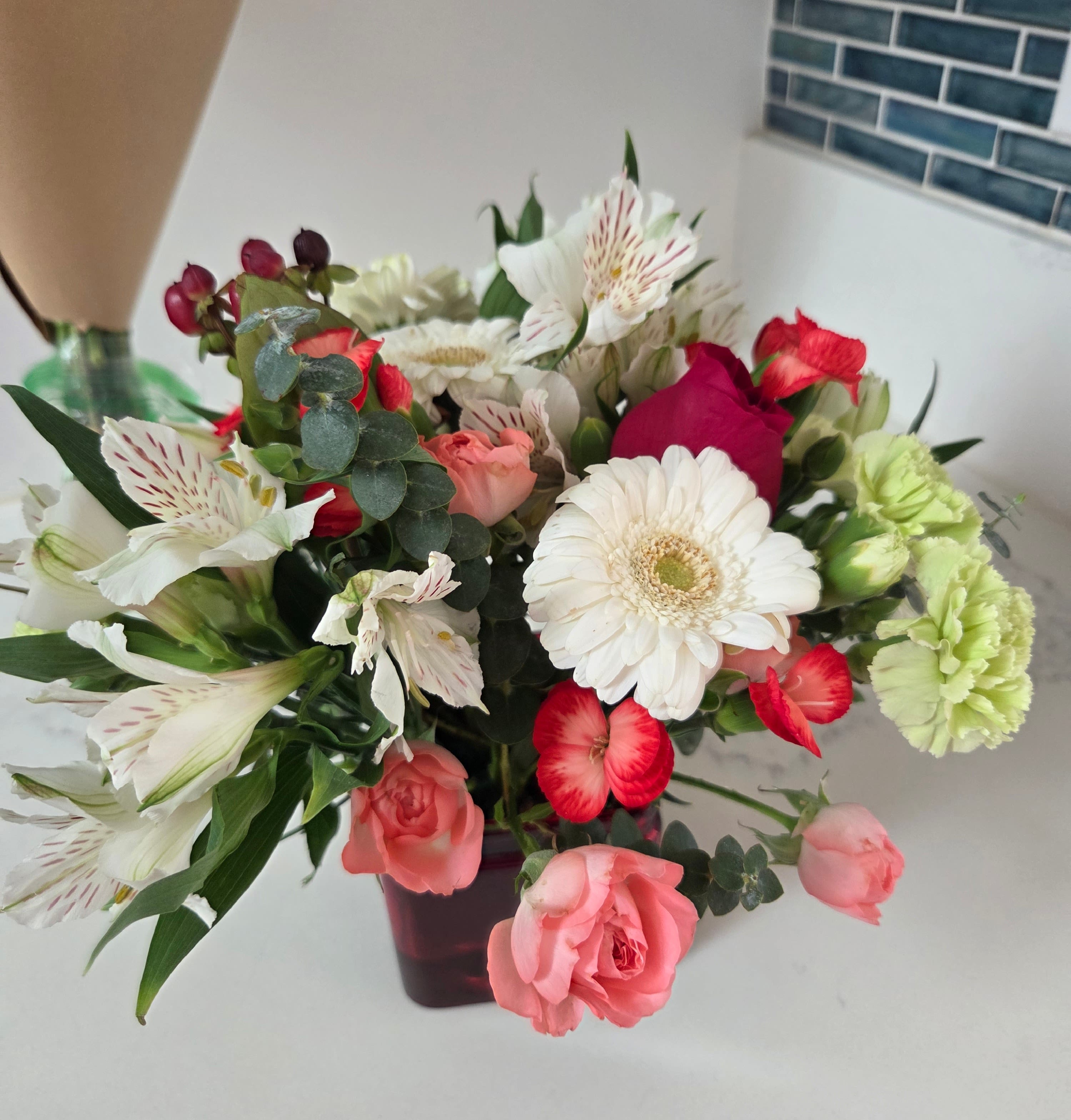 Cheer To You - A delightful white and green bouquet with a touch of red or pink. These versatile blooms fit a variety of occasions. Displayed in a red cube vase.