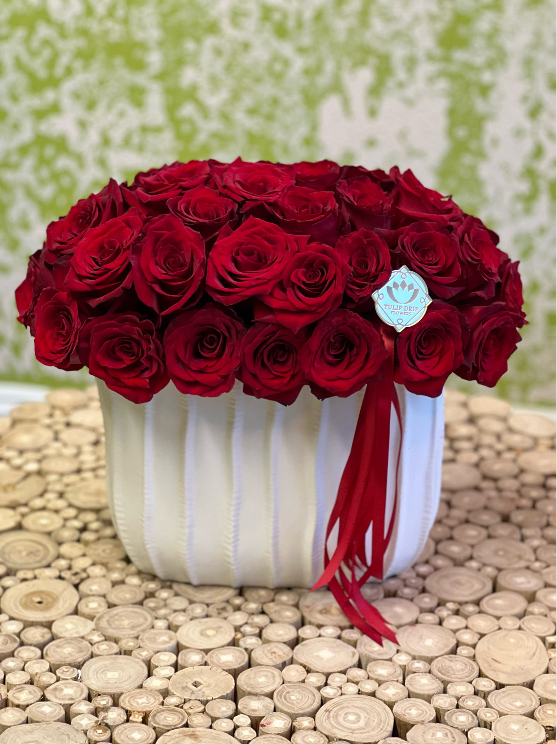 Scarlet Symphony – Mother’s Day - Elegant and compact, this white ceramic vase is filled with vibrant red roses and finished with a bold red ribbon. It’s a chic and modern way to say her “I love you”.