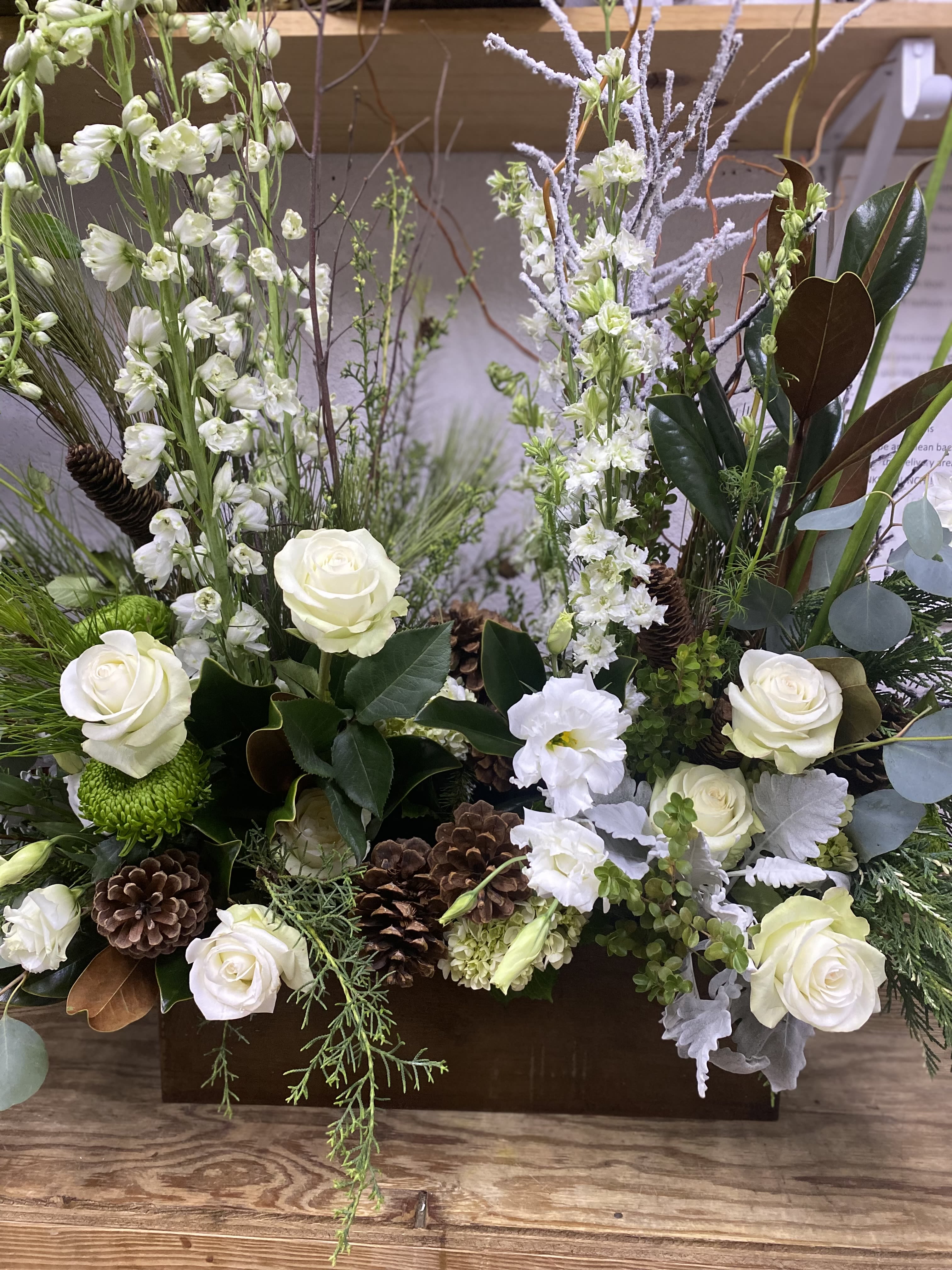 Winter White - White roses and white stock with other white blooms among greenery and snow-flocked birch branches and pine cones