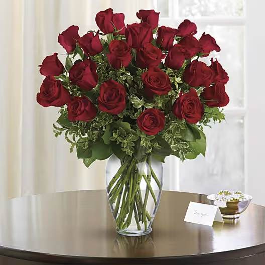 Two Dozen Red Roses (BB) - Indulge in the timeless allure of two dozen long stem red Ecuadorian roses elegantly presented in an 11" clear glass vase. Each exquisite rose exudes the essence of passion and romance, carefully selected from the lush fields of Ecuador for their vibrant crimson hues and velvety petals. This stunning arrangement captures the epitome of sophistication and grace, making it the perfect gift to convey love, admiration, and devotion.