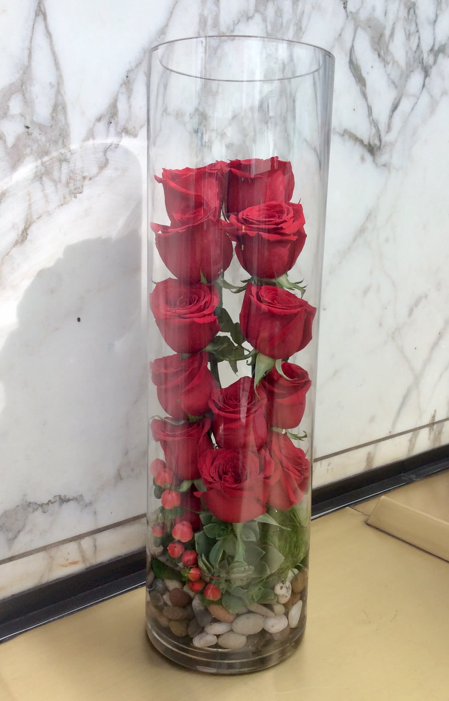 Sweet Romance - Beautifully arranged, in a unique style, this arrangement is sure to make a statement. Composed of a dozen red roses, succulents, river rocks in a cylinder vase.