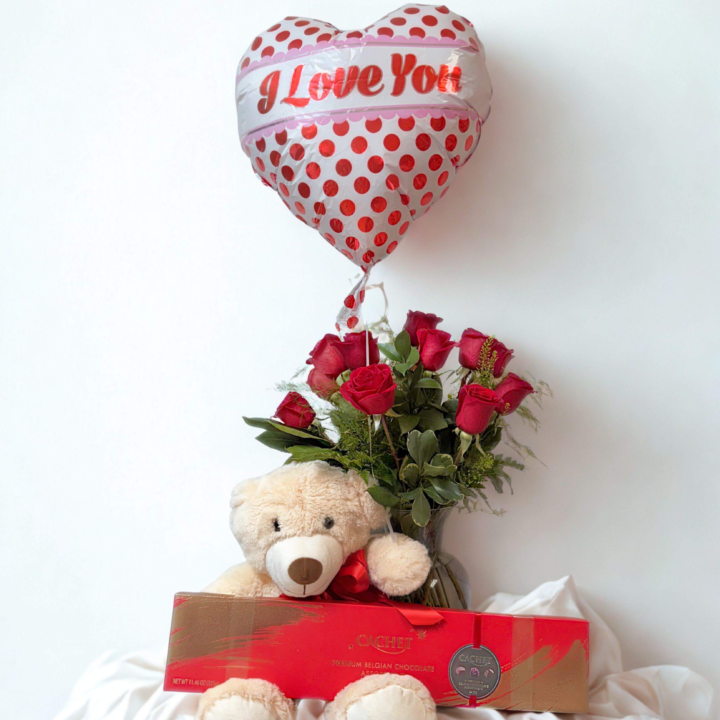 The Grand Gesture - The complete Valentine's Day package, all in one place. Includes one dozen red roses designed in a vase, a premium box of Belgium chocolates, a large plush teddy bear companion, and a Valentine's Day balloon.