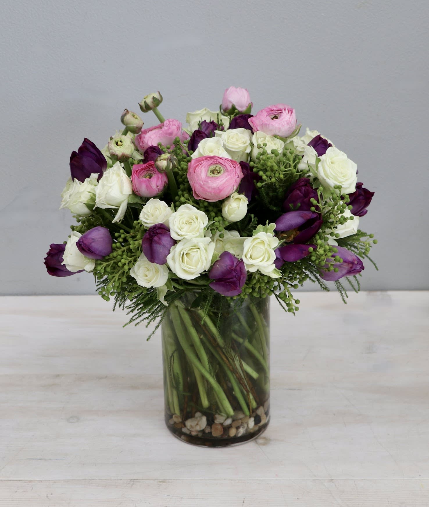 Simply Love - WeHo - The arrangement features spray rose, ranunculus, and tulips for a sweet look. At standard size this arrangement is 12-14 inches tall and wide.