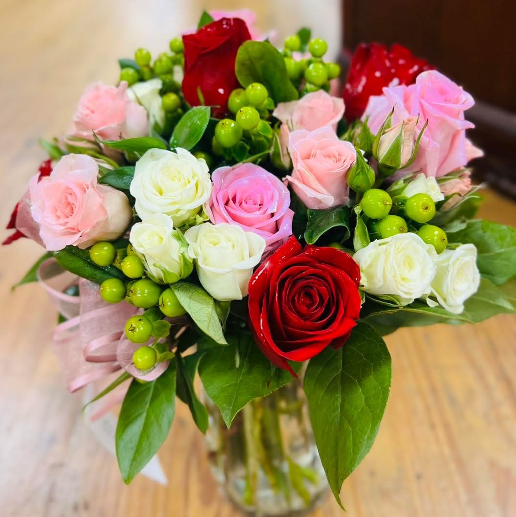 Simply Sophistication - Artfully designed and thoughtfully arranged, this bright and brilliant floral creation highlights the beauty of hot pink and red roses, as well as white spray roses, light pink spray roses, and green hypericum. A clear cylinder vase completes the design.