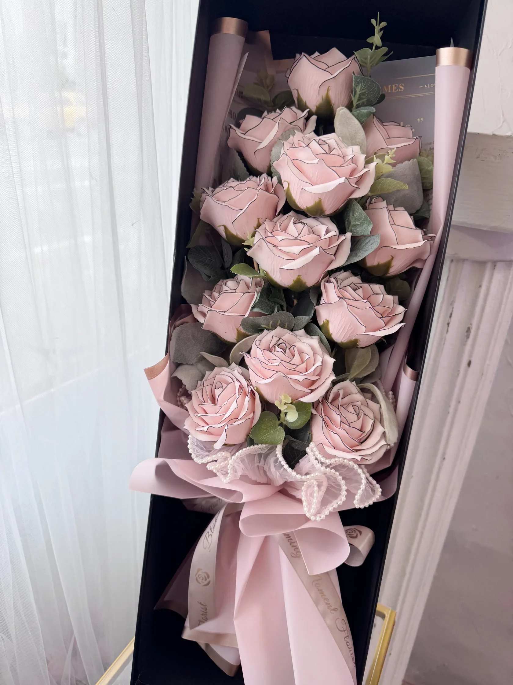 [SOAP FLOWER] Dozen Pink Liner Soap Rose Bouquet Long Gift Box - Elevate your gifting game with our SOAP FLOWER Dozen White Liner Soap Rose Bouquet. Adorned with 12 premium, large White Liner Roses and paired with the aromatic touch of Eucalyptus, this bouquet is sure to impress. Complete with a sleek black long gift box, it's the perfect present for any occasion. 