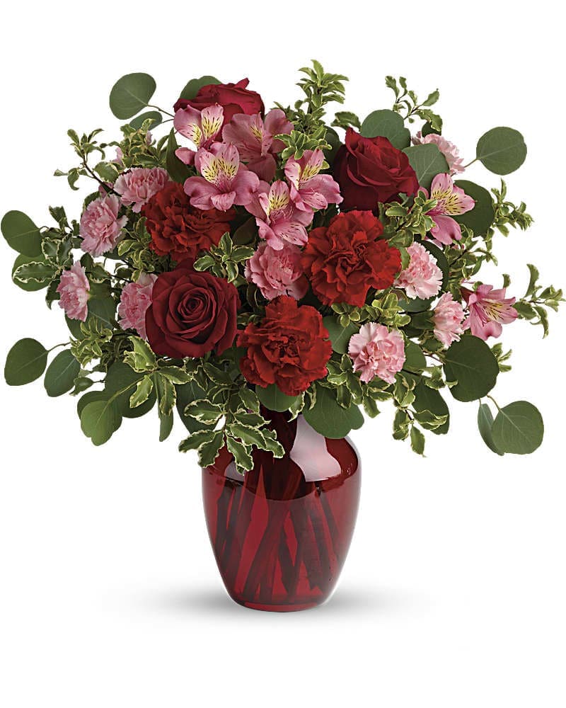 Blooming Belles Bouquet - The belle of the ball! Arranged in a ruby red vase this romantic bouquet of rich red roses and delicate pink alstroemeria is a beautiful statement of love and devotion. Red roses pink alstroemeria red carnations and miniature pink carnations are accented with silver dollar eucalyptus and pitta negra. Delivered in a ruby rose vase.