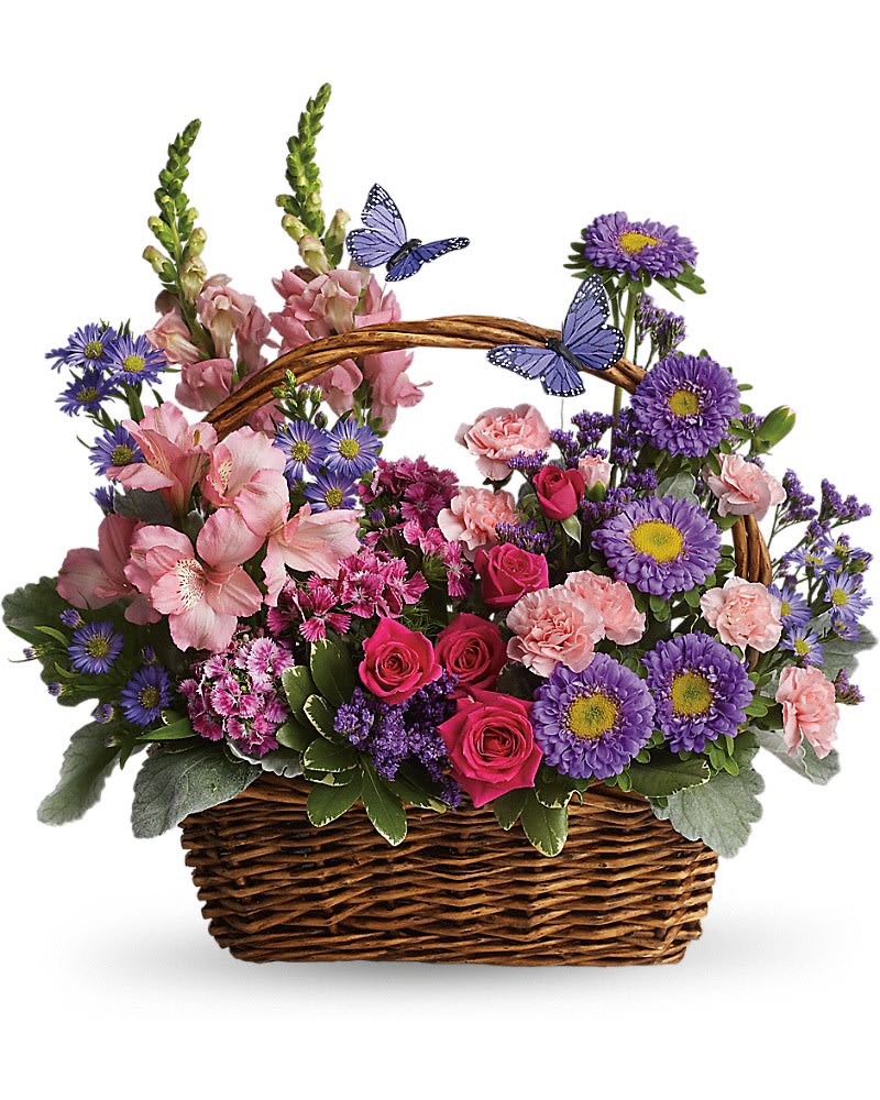 Country Basket Blooms - Talk about a bountiful basket! This wicker basket is overflowing with beauty and blossoms. It's no wonder two pretty butterflies have made this basket their home. Hot pink spray roses light pink alstroemeria snapdragons and miniature carnations dark pink Sweet William purple matsumoto asters large monte cassino asters statice and pittosporum fill a pretty picnic-like basket. You've got this gift handled!