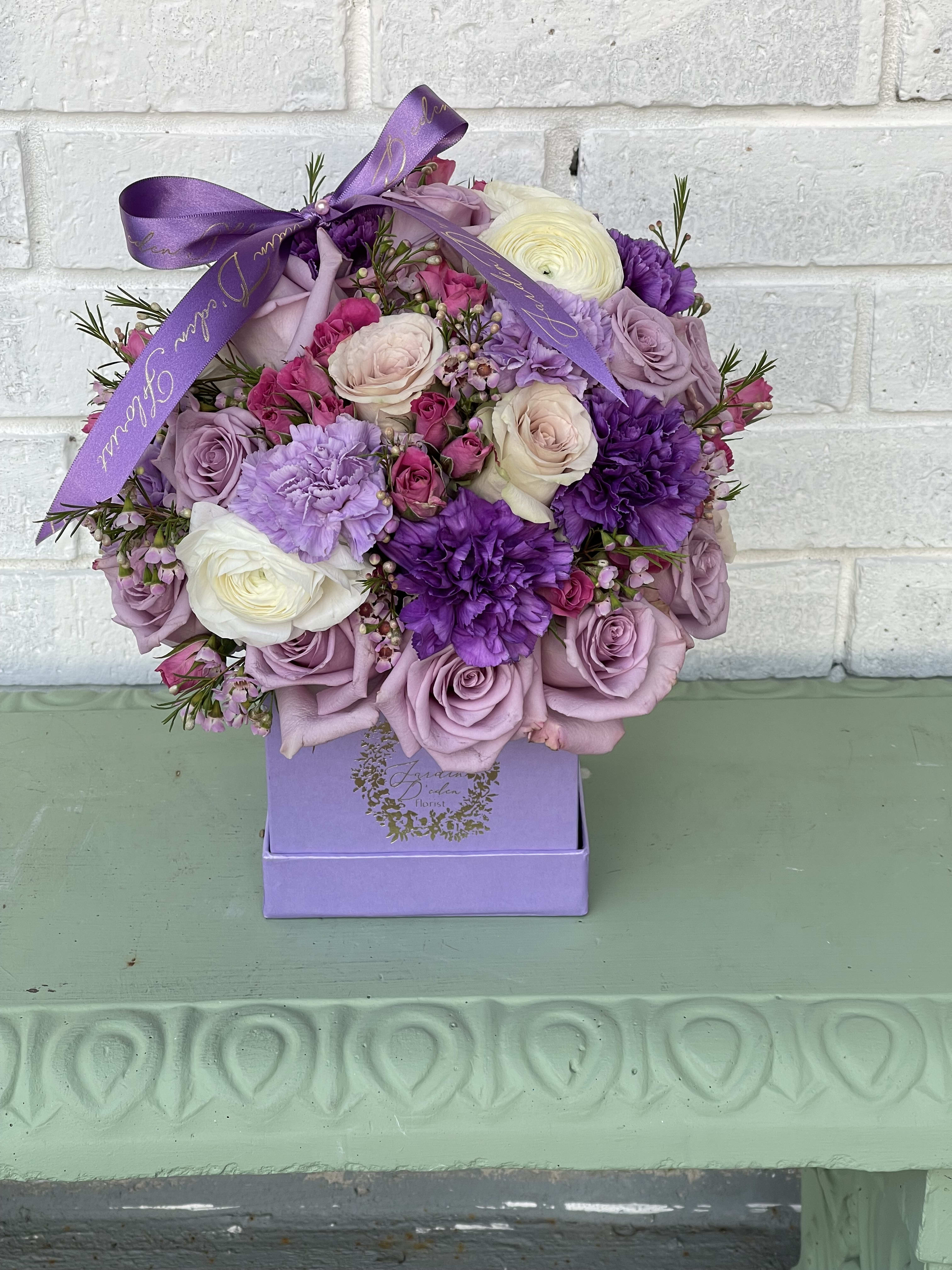 The lavender lady bloom box  - This is a square box filled with lavender roses, wax flower, carnations, spray roses and a variety of mixed fillers and flowers