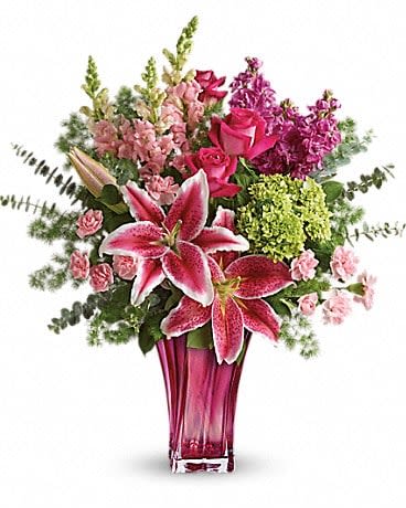 Teleflora's Steal The Spotlight Bouquet - When spoiling mom is the name of the game - steal the spotlight with this magnificent arrangement! Hand-delivered in a glorious glass blown vase, this luxe Mother's Day bouquet of fragrant lilies, roses, snapdragons and hydrangea will truly take her breath away. Pink stargazer lilies, pink snapdragons, pink stock, hot pink roses, green miniature hydrangea, and pink miniature carnations are accented with lemon leaf, ming fern, and spiral eucalyptus. Delivered in a Bold Elegance vase.