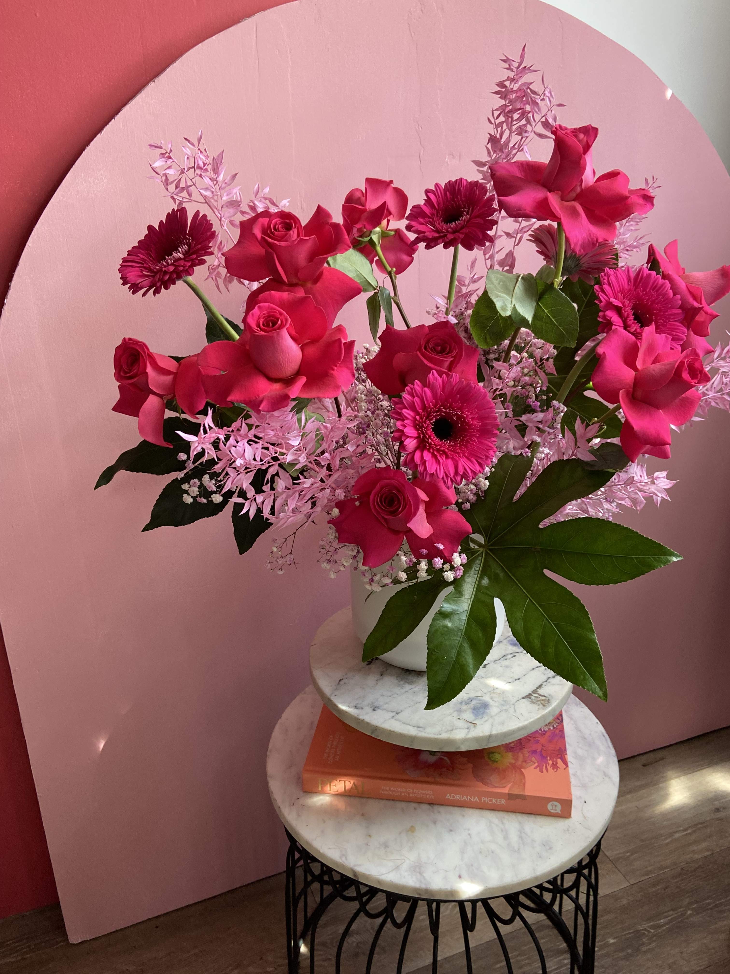 I'll have the Cosmo.  - Pink Monochromatic statement piece bursting with Pink Floyd roses, Gerber daisies, and Italian ruscus. Flexed Roses make this piece stand out amongst the rest. 