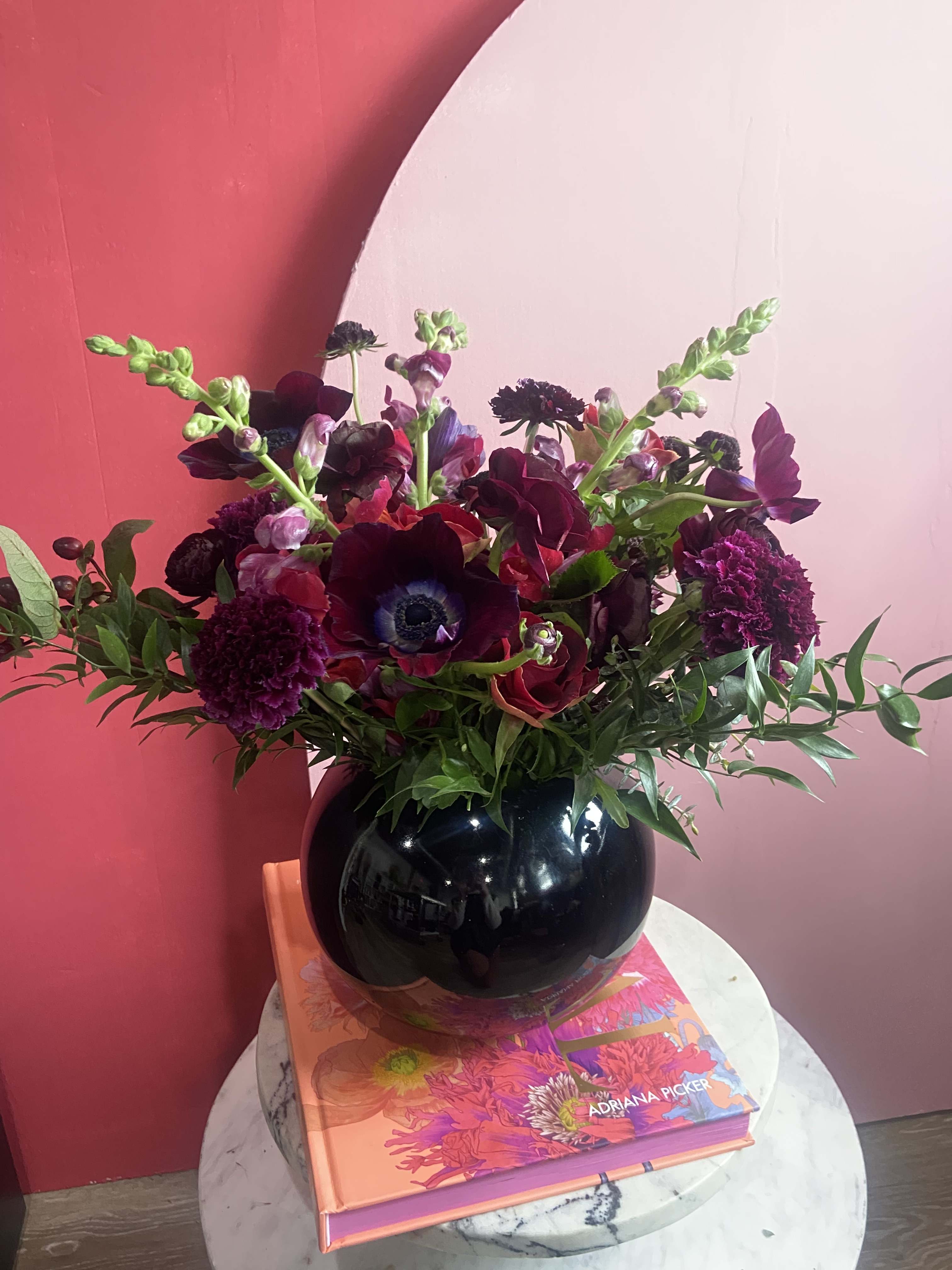 Velvet Cake - This delectable piece displays only the best premium blooms consisting of anemones, garden roses, orchids, scabiosa. Presented in a beautiful sleek black glass bubble bowl. 