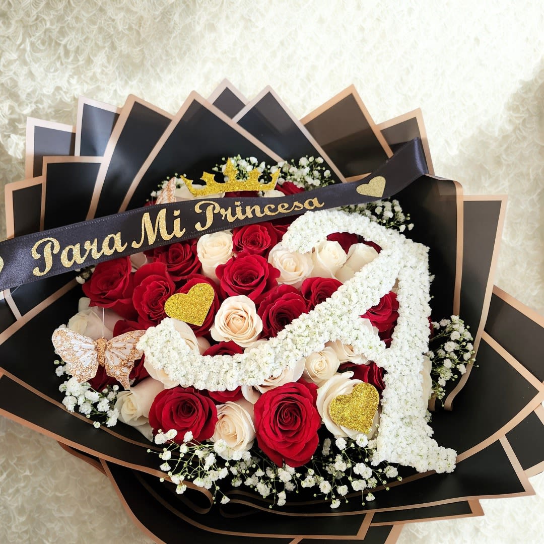 Mi Princesa Ramo by Latin Lady Luxe - Mi Princesa | Ramo Buchón  El Mi Princesa | Ramo Buchón es un diseño exclusivo creado para quienes desean regalar algo verdaderamente inolvidable. Cada ramo está elaborado a mano con 50, 75, o 100 rosas, seleccionadas por su frescura, tamaño y belleza. Su forma redonda y abundante crea un impacto visual inmediato, ideal para ocasiones especiales o para sorprender a la persona que más amas.  Este diseño incluye detalles artesanales que lo convierten en una pieza única:  - Letra personalizada hecha a mano con baby’s breath   - Corona decorativa en glitter (corte especial) — no es una tiara metálica   - Mariposas y corazones con brillo para un toque romántico   - Listón personalizado con vinil de lujo - Envoltura premium en negro y dorado   - Moños extra lujosos hechos a mano    Cada elemento es colocado con precisión y dedicación, asegurando que cada ramo sea único y completamente personalizado.   Un regalo perfecto para quienes merecen sentirse como una princesa.  Tamaño Regular 50 rosas Tamaño Deluxe 75 rosas Tamaño Premium  100 rosas