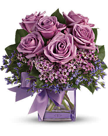Teleflora's Morning Melody - Fresh as morning dew. Beautiful blooms in all shades of purple are gathered into a purple glass cube vase and tied with a purple bow. How perfectly purple! A pretty taffeta ribbon puts the finishing touch on this presentation of lavender roses, lavender waxflower, purple limonium and rich green salal. Delivered in a purple glass cube vase.