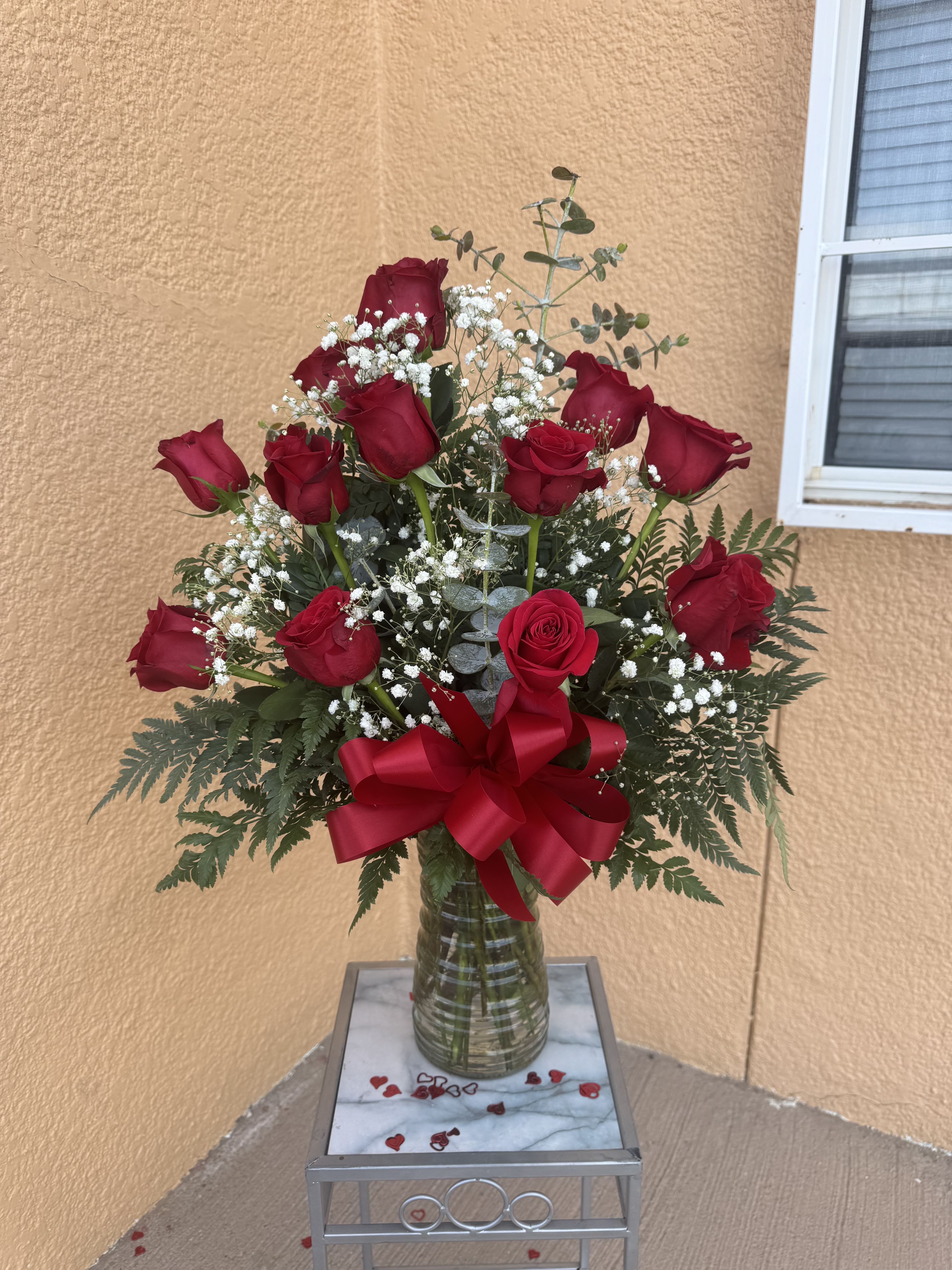 One Doz  Red Roses in an arrangement  - Elegant and timeless, this beautiful arrangement features fresh premium red roses accented with delicate baby’s breath and lush greenery, finished with a romantic satin bow in a clear glass vase. Perfect for anniversaries, romantic occasions, or sending a heartfelt surprise. Same-day delivery available in El Paso.