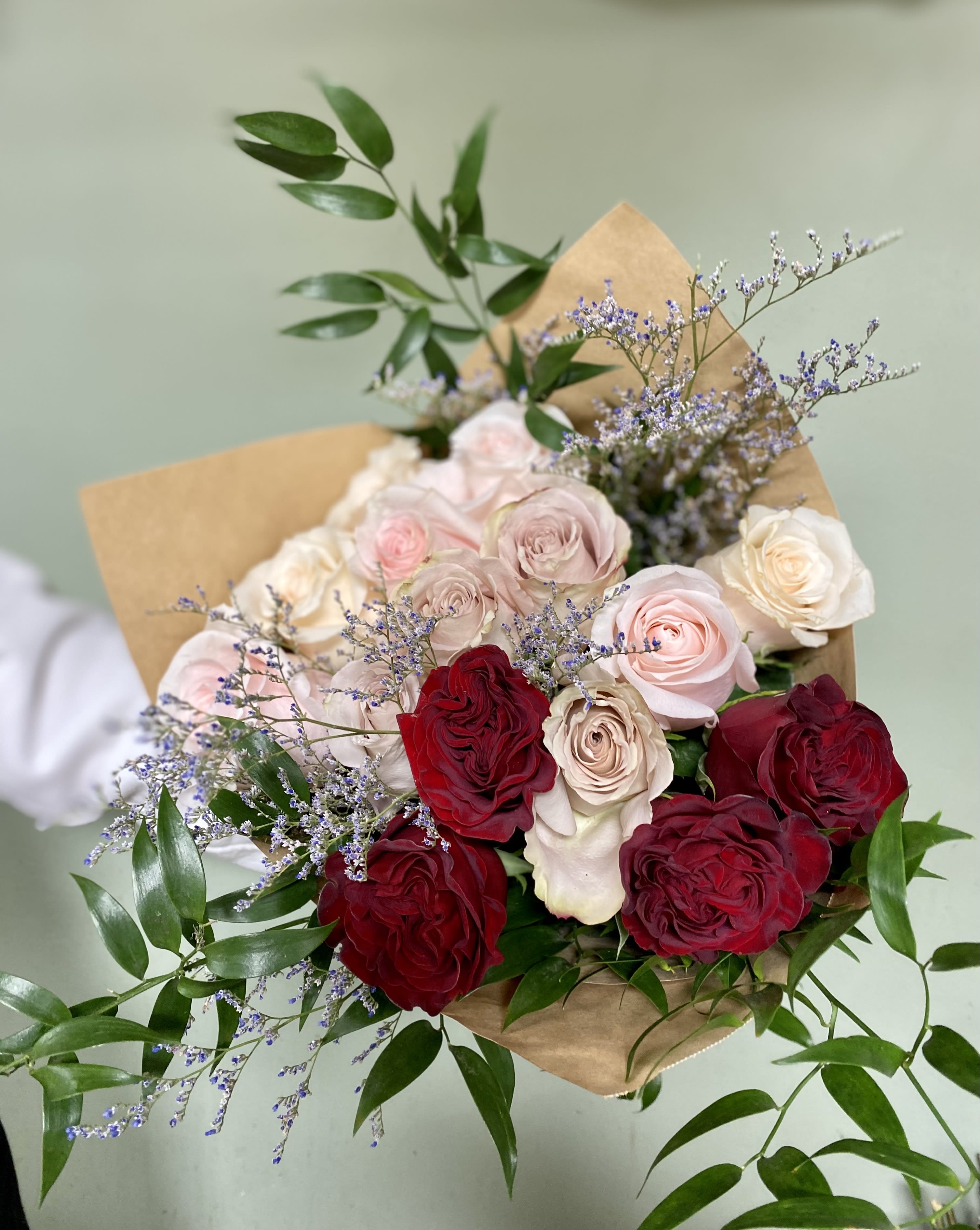 Enchanted Roses - This bouquet includes a dozen and a half roses of three different shades with misty and greenery wrapped in brown paper.