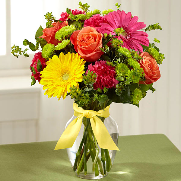 The FTD Bright Days Ahead Bouquet - Celebrating life with colorful blooms that inspire and delight this flower bouquet is ready to create a happy moment for your recipient that they will never forget. Orange roses hot pink gerbera daisies yellow gerbera daisies hot pink carnations green button poms bupleurum and lush greens mingle together to create a sunlit display while seated in a classic clear glass vase tied at the neck with a yellow satin ribbon for a sweet affect. A perfect get well happy birthday or congratulations gift! 