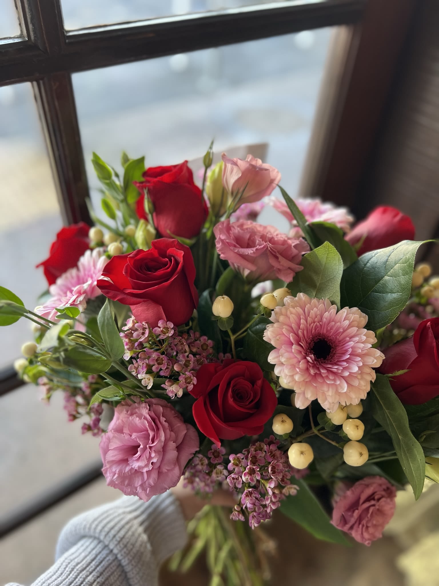 Map to my Heart Hand-Tied Bouquet  - Tell her you love her with this stunning hand-tied bouquet! It contains red roses, pink lisianthus, cream hypericum berries, purple wax flower, and gerber daisy’s. ***Please note: this is a hand-tied bouquet and price listed does NOT include vase.*** Vase can be added for additional charge. Prices may vary. 
