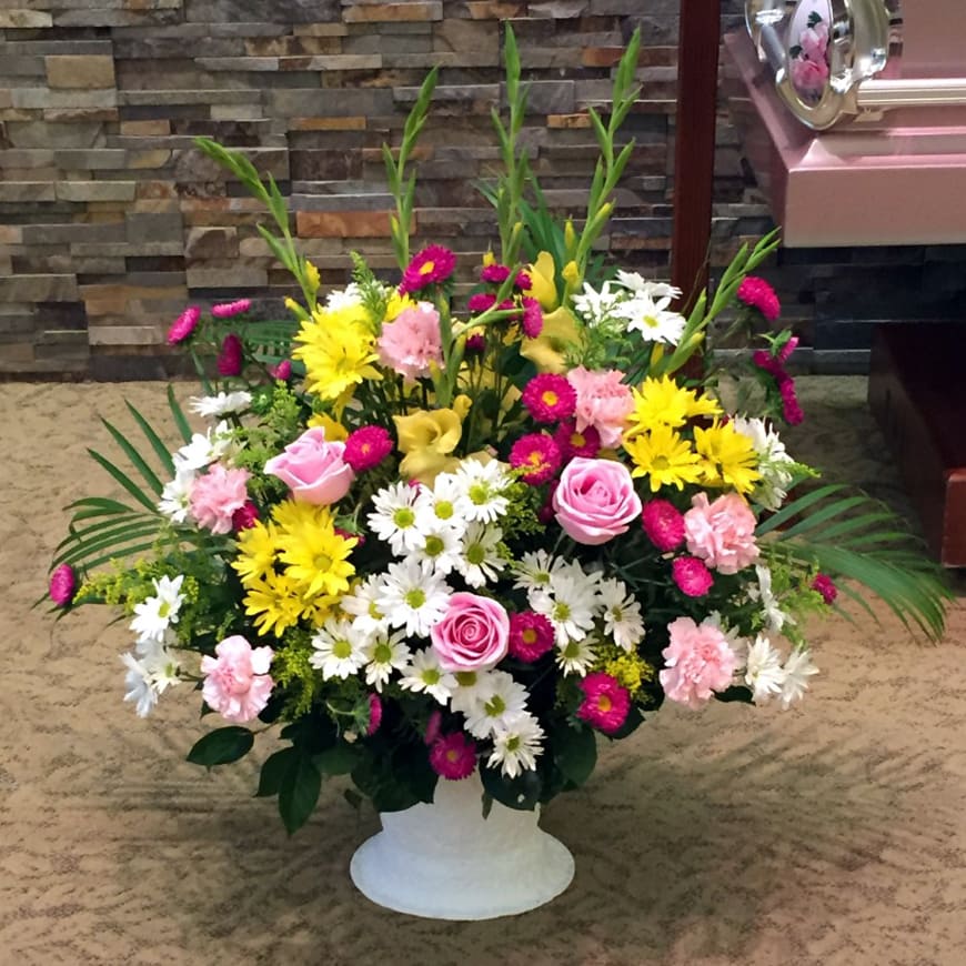 Classic Sympathy Basket - Our classic basket of traditional flowers displays an abiding faith to all who attend the service. It features Roses, Carnations, Alstromeria, Daisies, Gladiolus, Chrysanthemums and other seasonal flowers. Presented here with pink, yellow &amp; white flowers, though please note that more color choices are available! You can specify the colors that you prefer in a special comments box during your check-out process, or just give us a call at 619-237-8842.   This one-sided design is suitable to send to a residence, a funeral home or service. Take advantage of our arrangement size upgrade options. Standard size is approximately 26in (W) x 36in (H). Deluxe and Premium versions are a bit larger and have more premium blooms.
