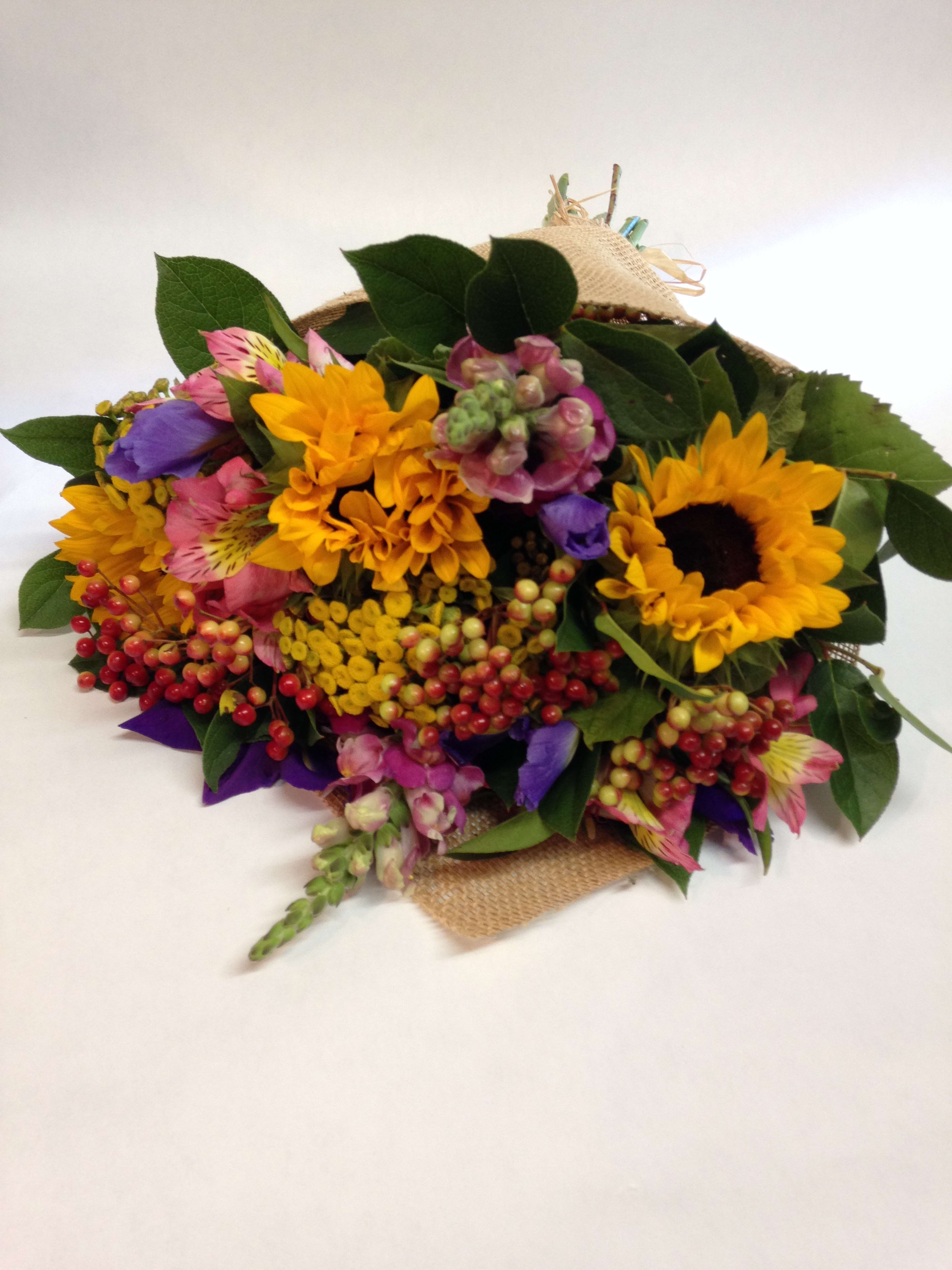 Backyard Garden Wrap - Our Backyard Garden arrangement but all wrapped together with burlap.  This arrangement includes yarrow, sunflowers, varigated berries, snapdragons, irises, astroemeria and various seasonal greenery.  (Some flowers may be subject to change depending on the season. We will contact you with available flower substitutions; please contact us with specific questions if you are concerned with flower availability, thanks!)  Featured arrangement: $78.75 (Regular Price)