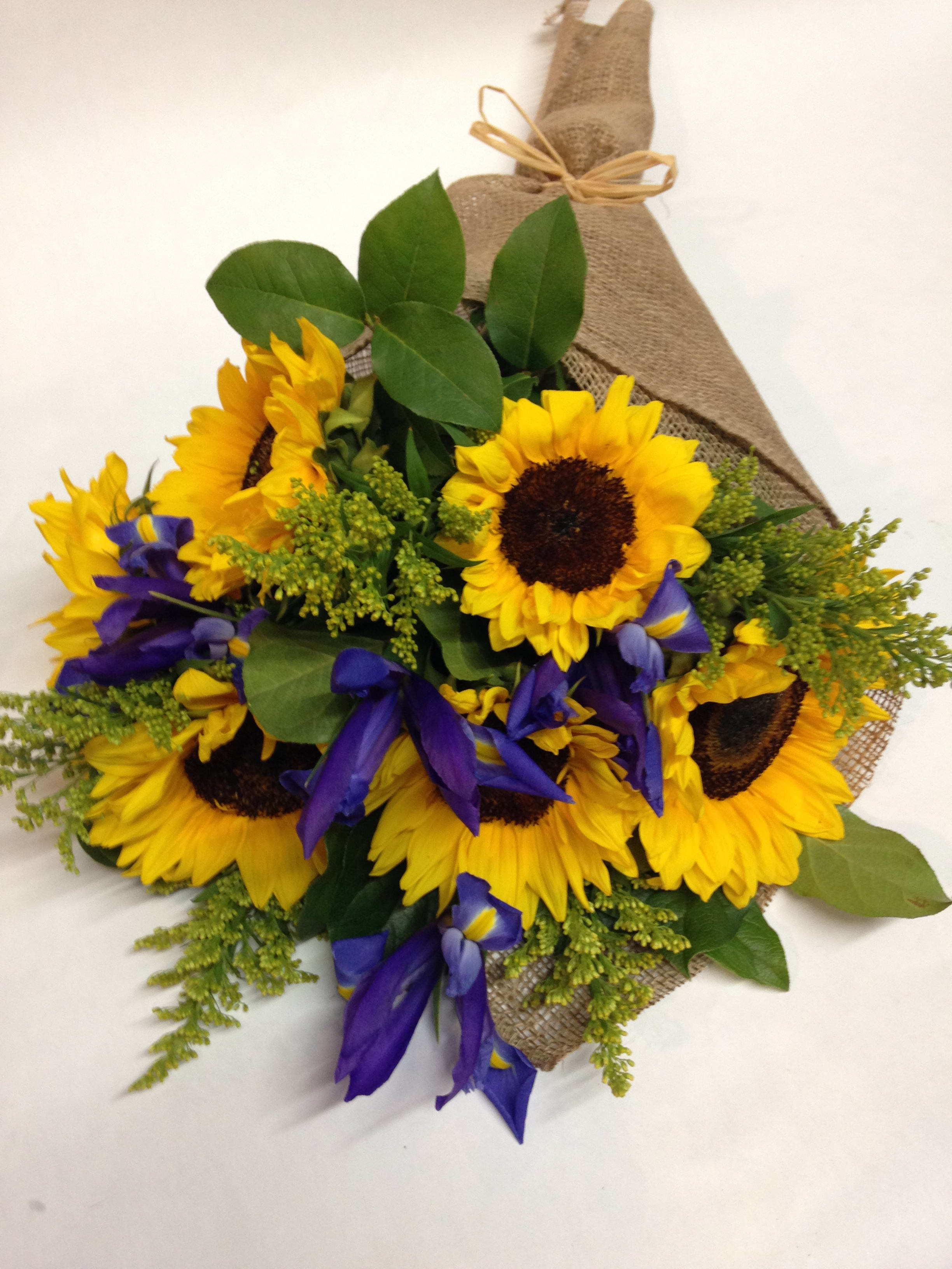 Bouquet of sunflowers and purple irises wrapped in burlap