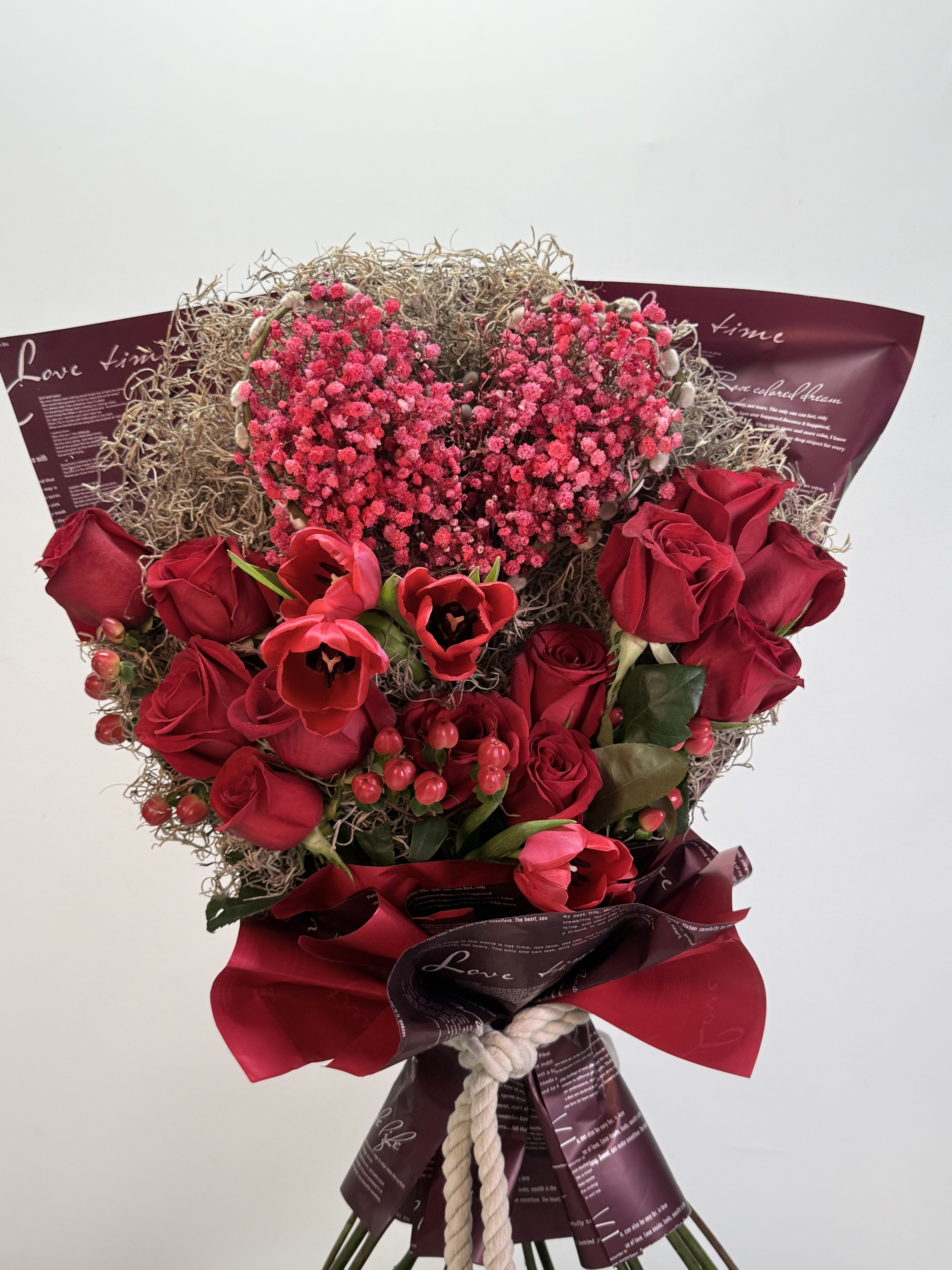 Crimson Heart Romance - An elegant, romantic bouquet featuring premium red roses, red tulips, and delicate heart-shaped floral accents, hand-wrapped with a refined finish. Designed to express deep love and make any special moment unforgettable.  Substitution &amp; Design Policy  AS SIMILAR AS POSSIBLE  Each floral arrangement is custom-designed and handcrafted using the freshest flowers, containers, decorative accents, and materials available at the time of creation. Due to seasonal availability, immediate inventory conditions, market limitations, or unforeseen circumstances, substitutions of flowers, containers, or decorative elements may be necessary.  When substitutions occur, they will always be made with items of equal or greater value, while preserving the overall style, color palette, proportions, and design integrity of the original arrangement. The final product will be delivered as similar as possible to the design shown.  By placing an order, you acknowledge that all floral designs are unique and that natural variations are part of the artistic and handcrafted process. Our commitment is to deliver the most beautiful and refined version of each arrangement, consistent with our quality standards.