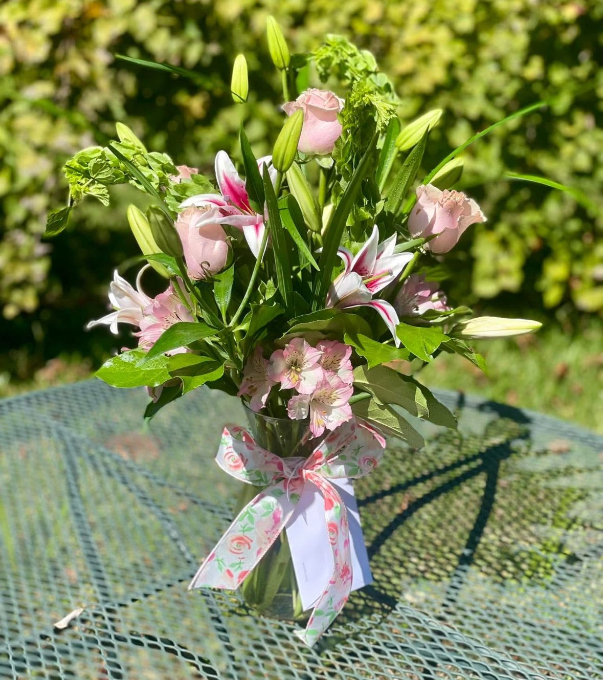Elegant Garden Bloom Bouquet  - Stunning arrangement crafted to impress. Nestled in a clear glass vase tied with a floral ribbon. Featuring Stargazer lillies, pink roses, belles of Ireland, and pink alstroemeria