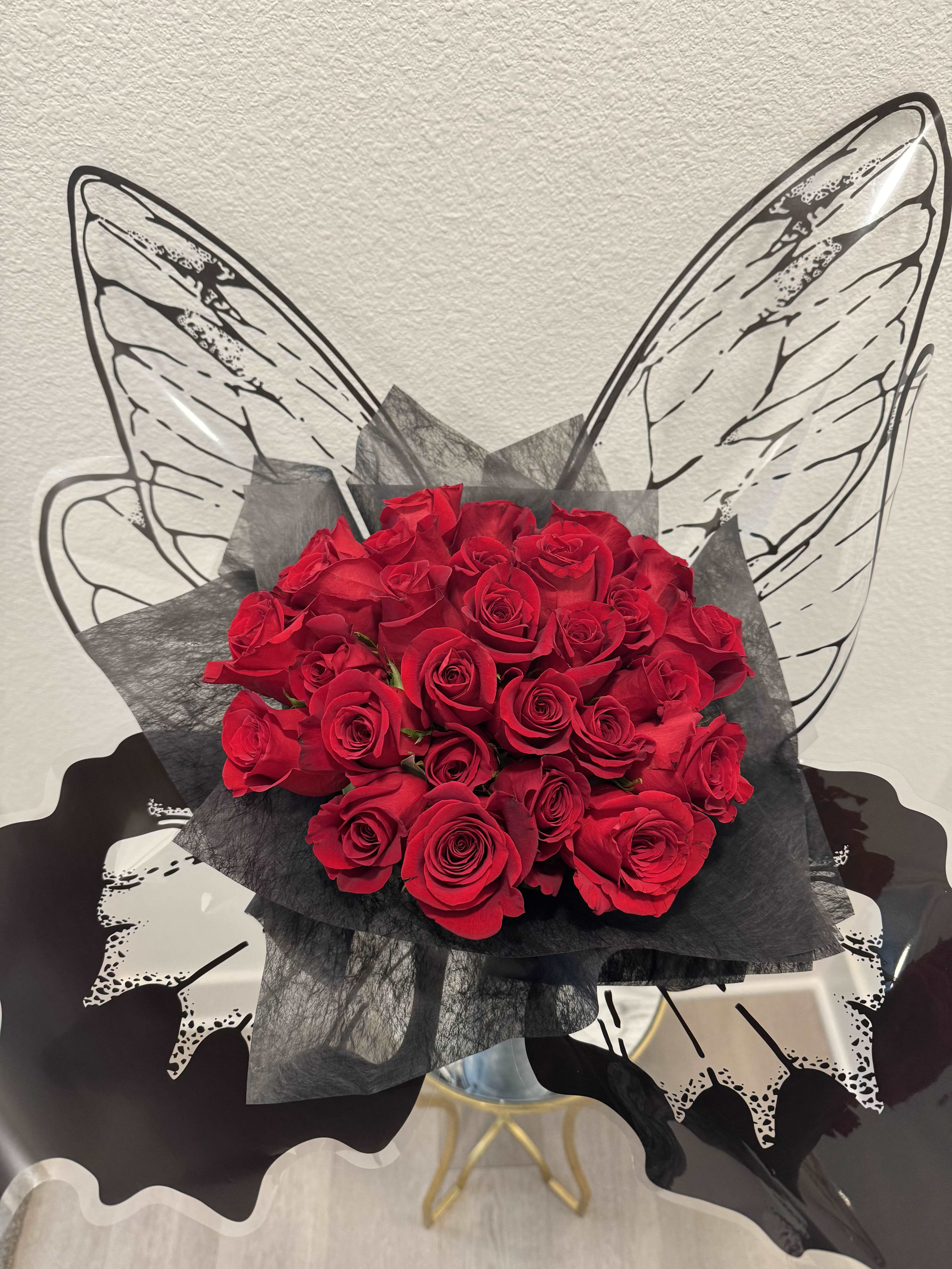 Black Butterfly  - A graceful arrangement of rich red roses adorned with a classic black butterfly wrapped delicately around the bouquet. Elegant and enchanting, this design is a symbol of beauty, transformation, and everlasting love.