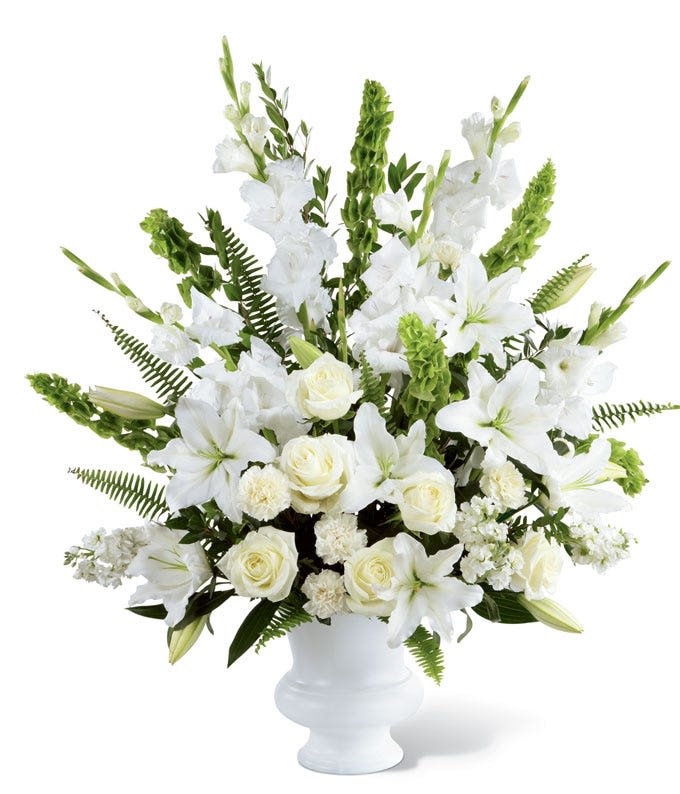 Celestial Bloom - A serene standing arrangement of white lilies, roses, snapdragons, and lush greenery. Designed with elegance and reverence, this large pedestal honors a life with purity, peace, and grace.