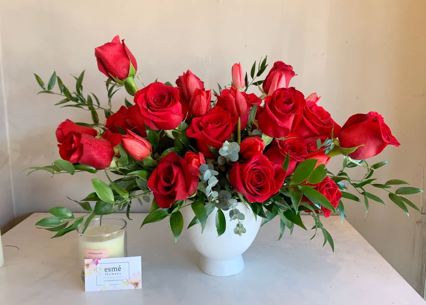 Crush Mode - A classic red rose arrangement with a modern twist of elegance. The arrangement features premium freedom roses and tulips, arranged in a beautiful pedestal vase.