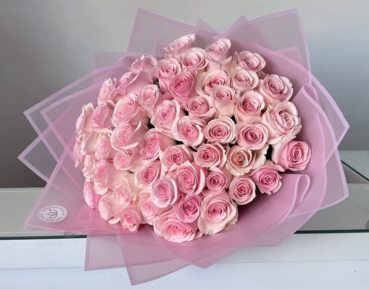 50 Pink Roses Bouquet - 50 long stem roses in wrapping. Radiant and romantic, our 50 Pink Roses Bouquet is the ultimate expression of admiration, gratitude, and affection. With fifty lush, long-stemmed pink roses wrapped in elegant pastel paper, this bouquet makes a stunning gift that is as charming as it is memorable. Perfect for celebrating love, milestones, or simply showing how much you care.   •    50 premium pink roses hand-selected for freshness     •    Wrapped in soft pastel paper with a refined finish     •    Represents admiration, sweetness, and elegance     •    Ideal for anniversaries, birthdays, romantic gestures, or special celebrations  VASE NOT INCLUDED