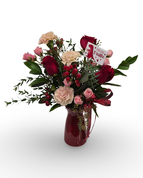 Love-O-Saurus - Love-o-saurus is a fun and flirty arrangement featuring rich red roses, soft blush blooms, and fresh greenery accented with playful texture. Finished with an adorable dinosaur pick for an extra touch of charm, this bouquet is designed in a deep red glass vase and measures approximately 16 x 12 inches. 