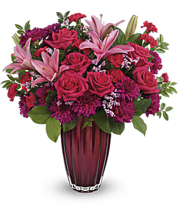 Modern Devotion - Your devotion knows no bounds. Celebrate your love this Valentine's Day with this stunning rose and lily bouquet, artfully arranged in a magnificent European glass vase with pearlescent finish. This arrangement includes hot pink roses, pink asiatic lilies, fuchsia carnations, miniature red carnations, pink cushion spray chrysanthemums, pink limonium, lemon leaf and huckleberry. This Valentine's Day bouquet is delivered in Teleflora's Modern Devotion vase.