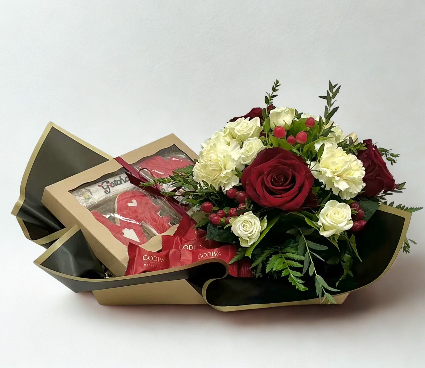 "Love at First Bite" Floral Gift Box - A romantic floral gift box featuring a low arrangement of lush red roses and delicate white accents, paired with a boxed set of handmade, Valentine’s-themed decorated sugar cookies by Sweet Sanction—the perfect blend of beauty and sweetness.
